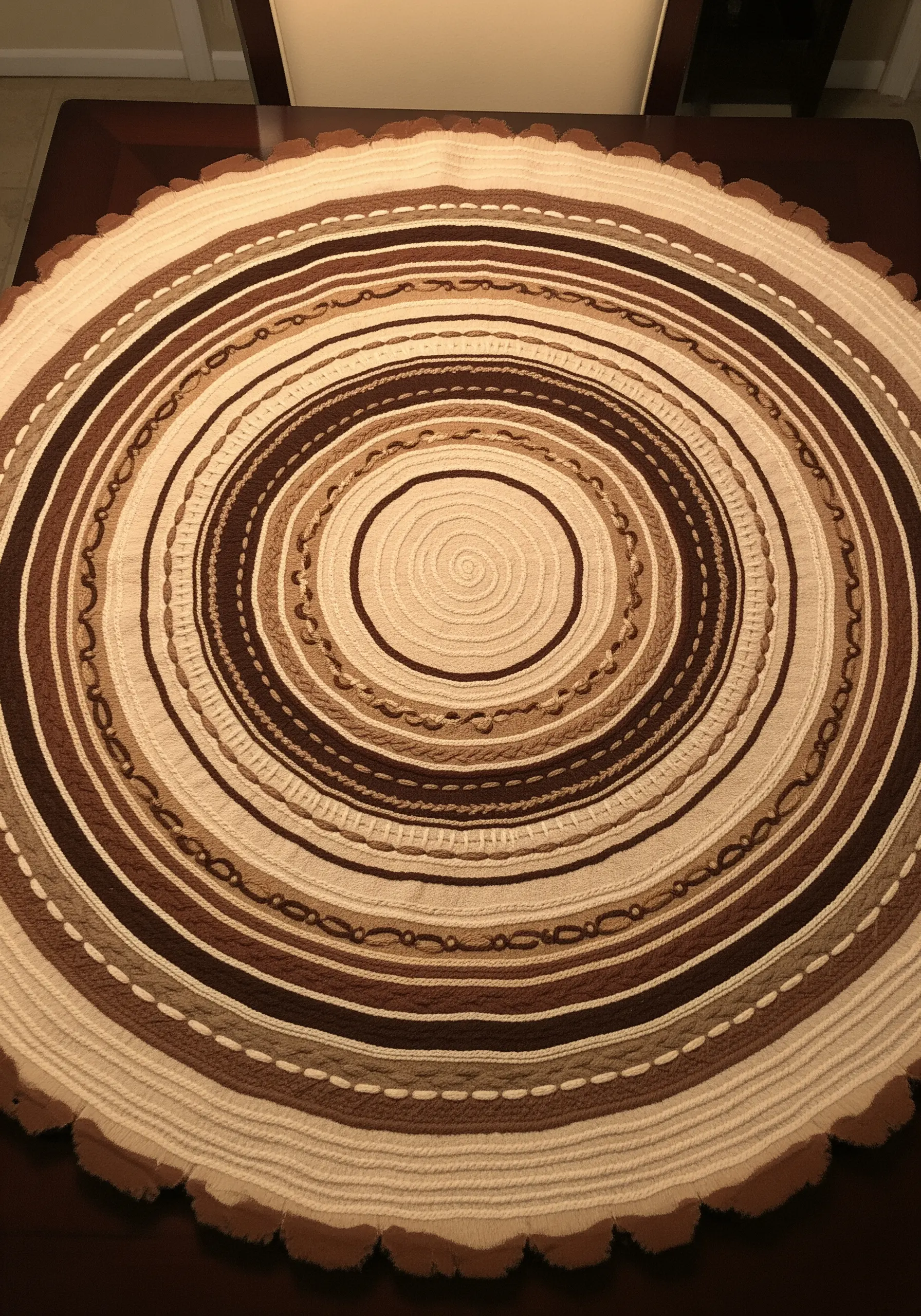 A large, circular embroidered piece mimicking tree rings with different brown and beige yarns.