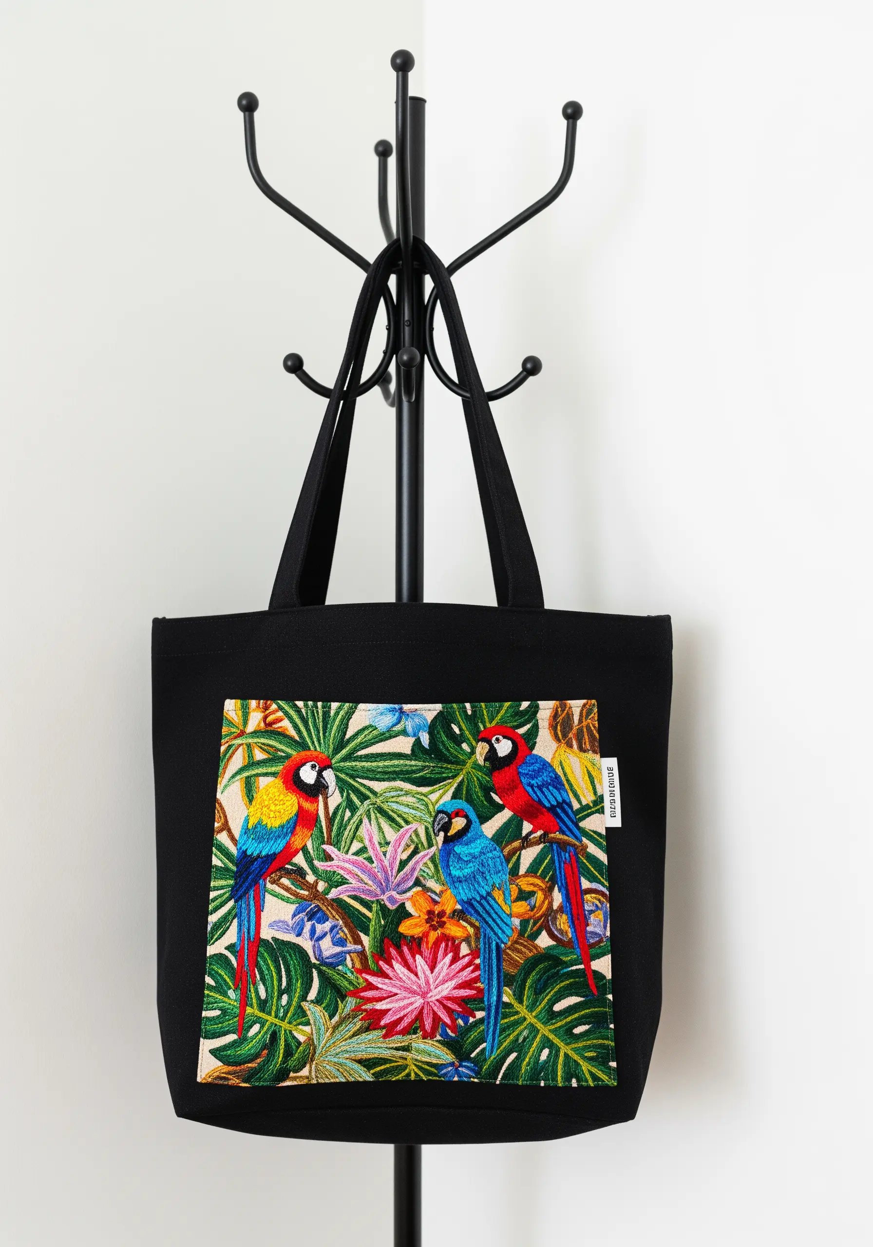 Black tote bag embroidered with three colorful parrots and tropical leaves