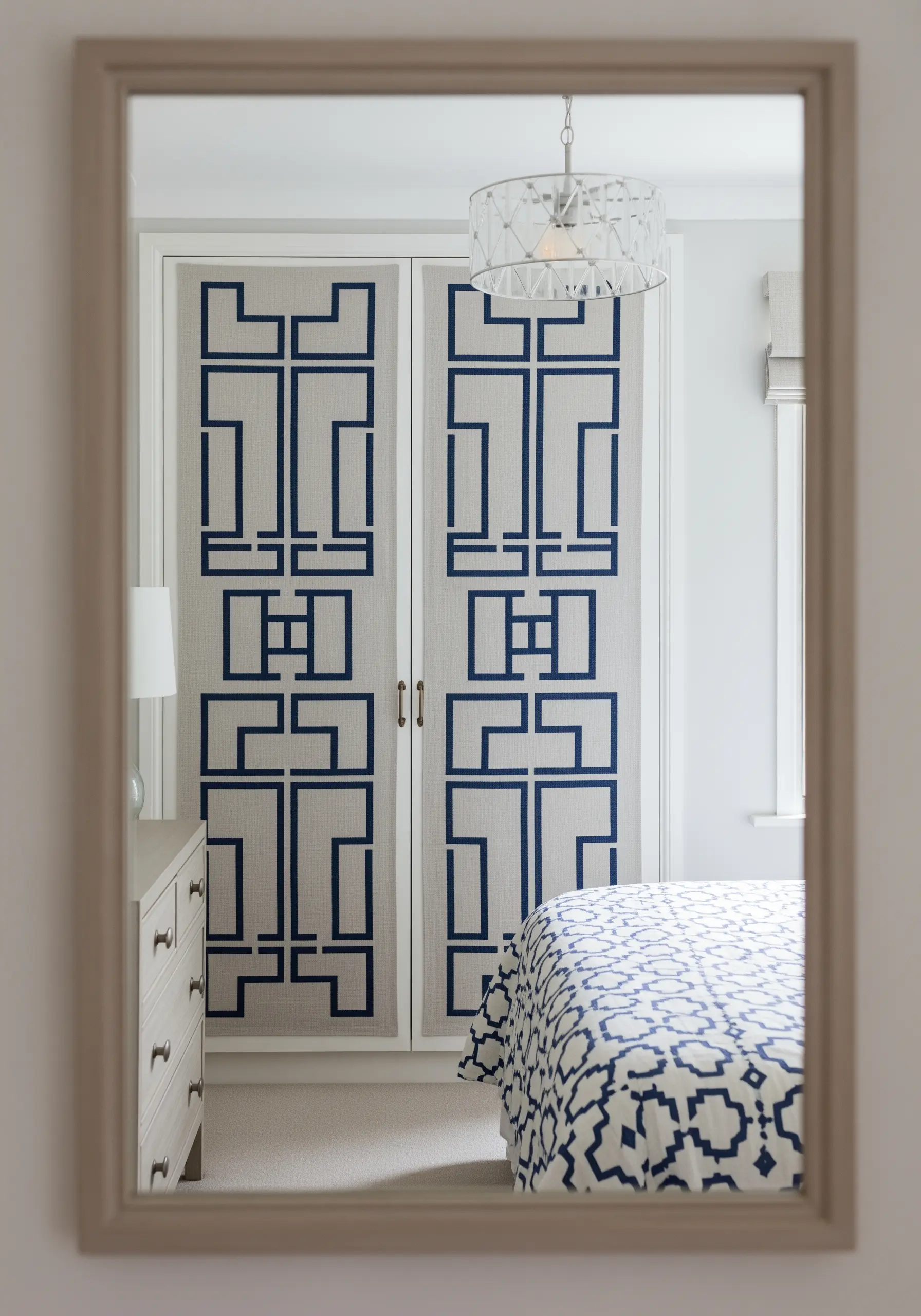 Closet doors upholstered in linen with a bold, geometric blue appliqué pattern.