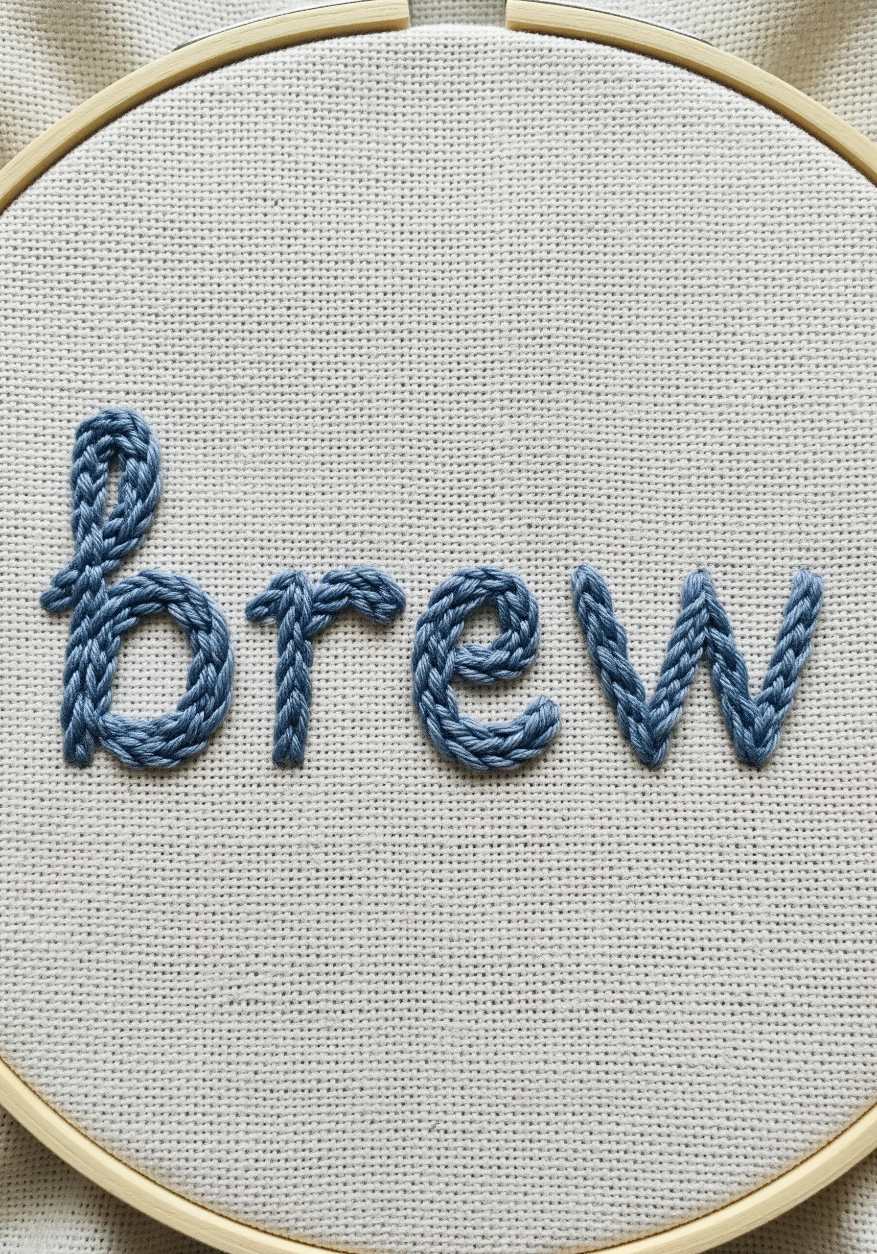 The word 'brew' embroidered in a thick, textured blue chain stitch.