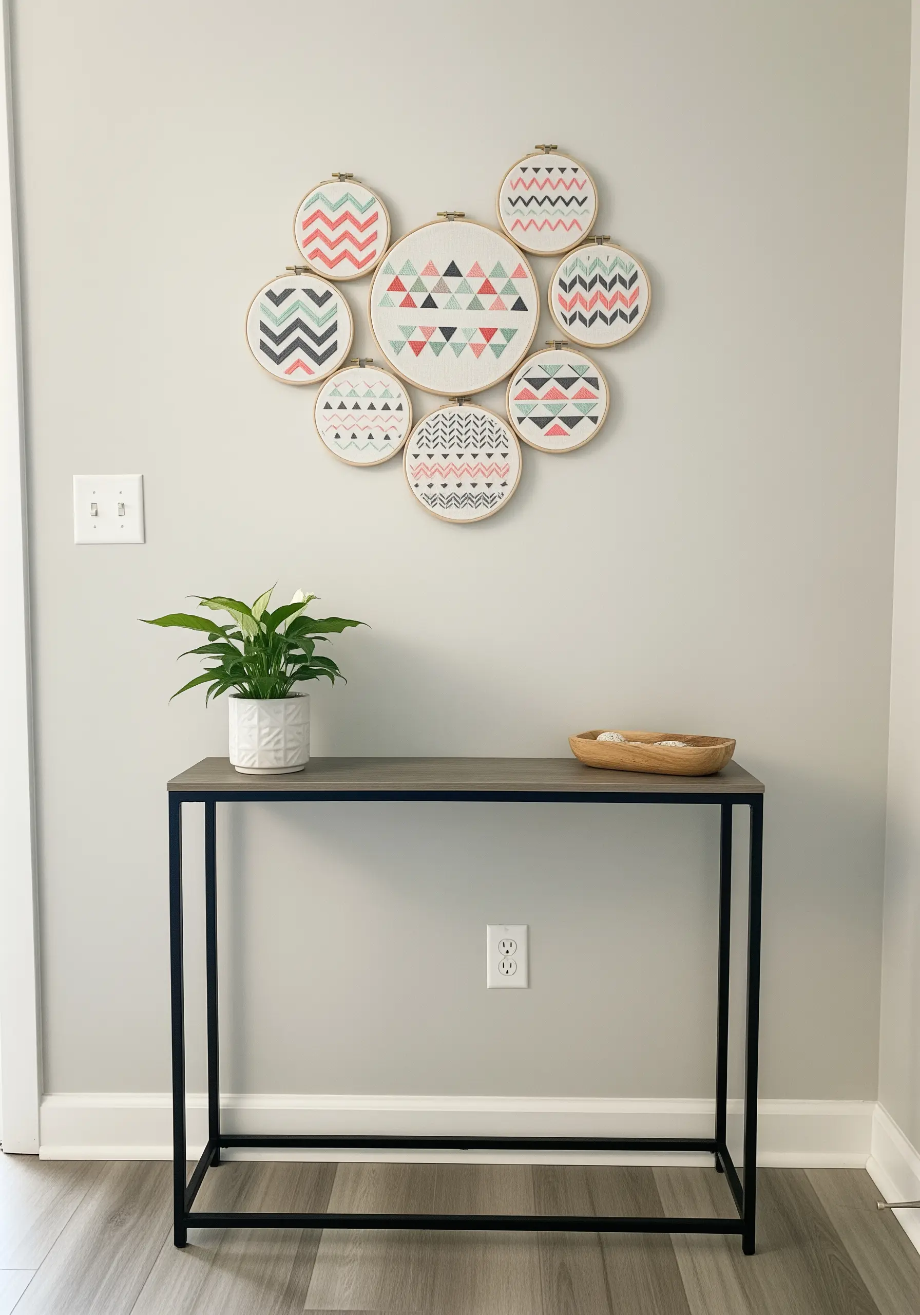 A gallery wall of eight embroidery hoops with modern geometric patterns in a cohesive color palette.