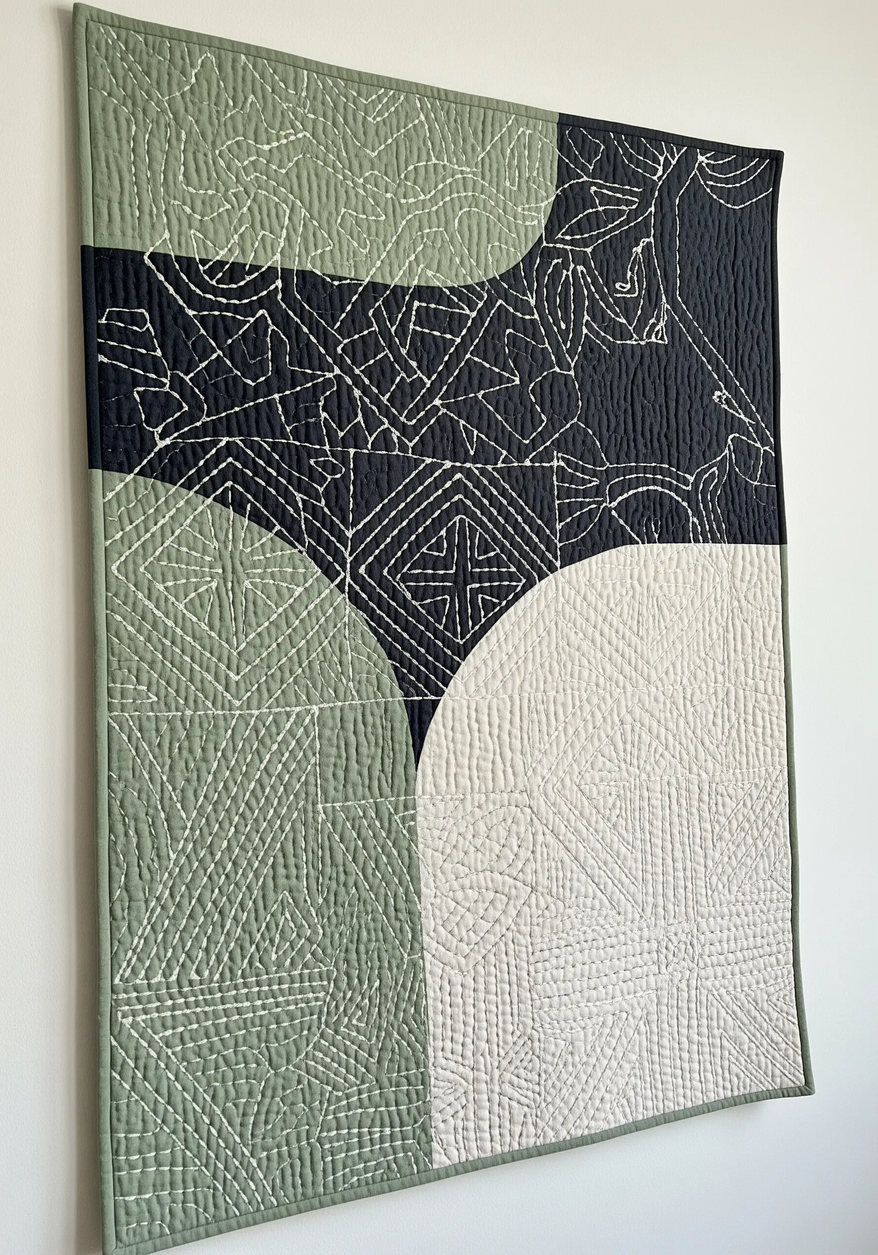 A modern quilt with color-blocked fabric unified by continuous hand-stitched lines.