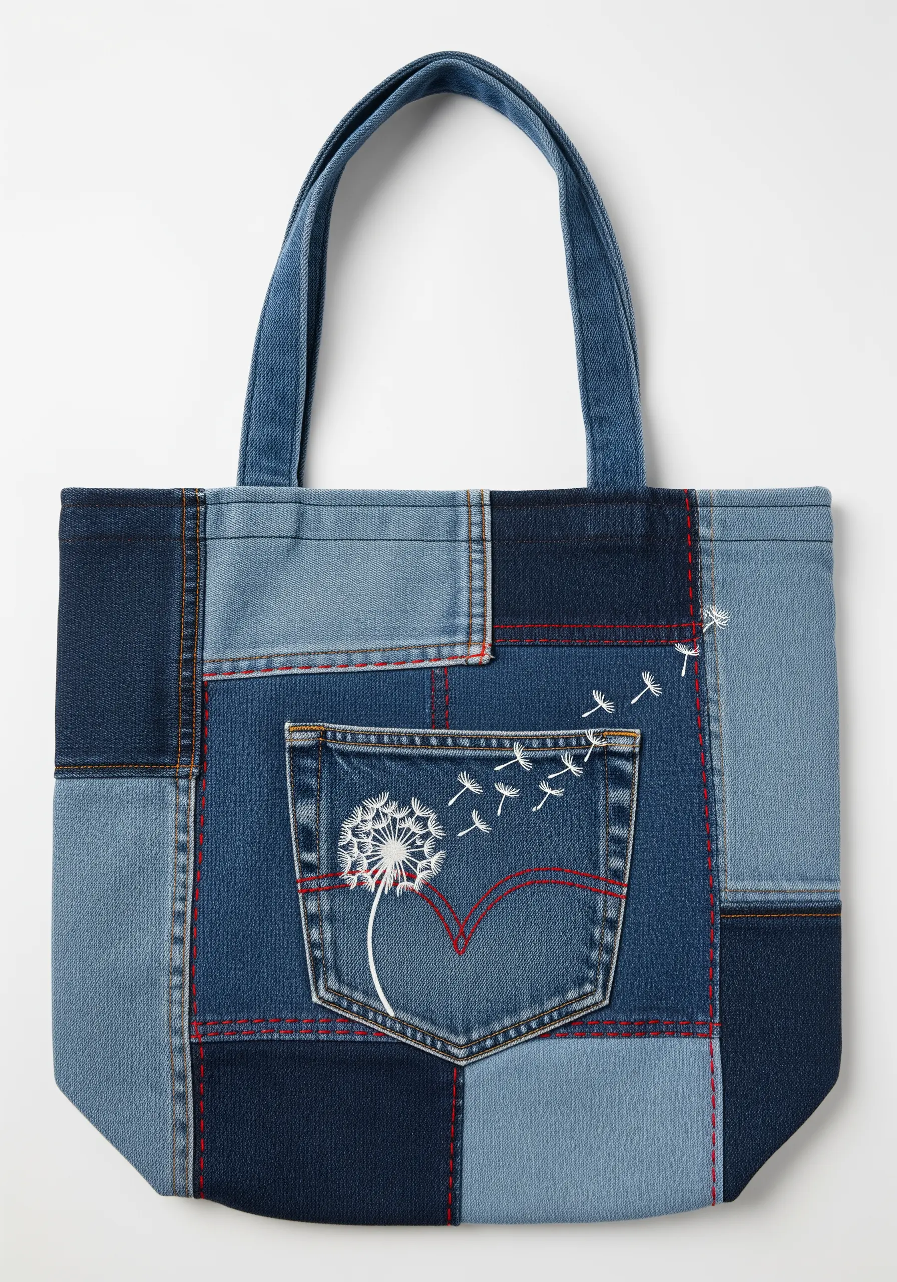 Dandelion embroidered in white on the pocket of an upcycled denim patchwork tote bag.
