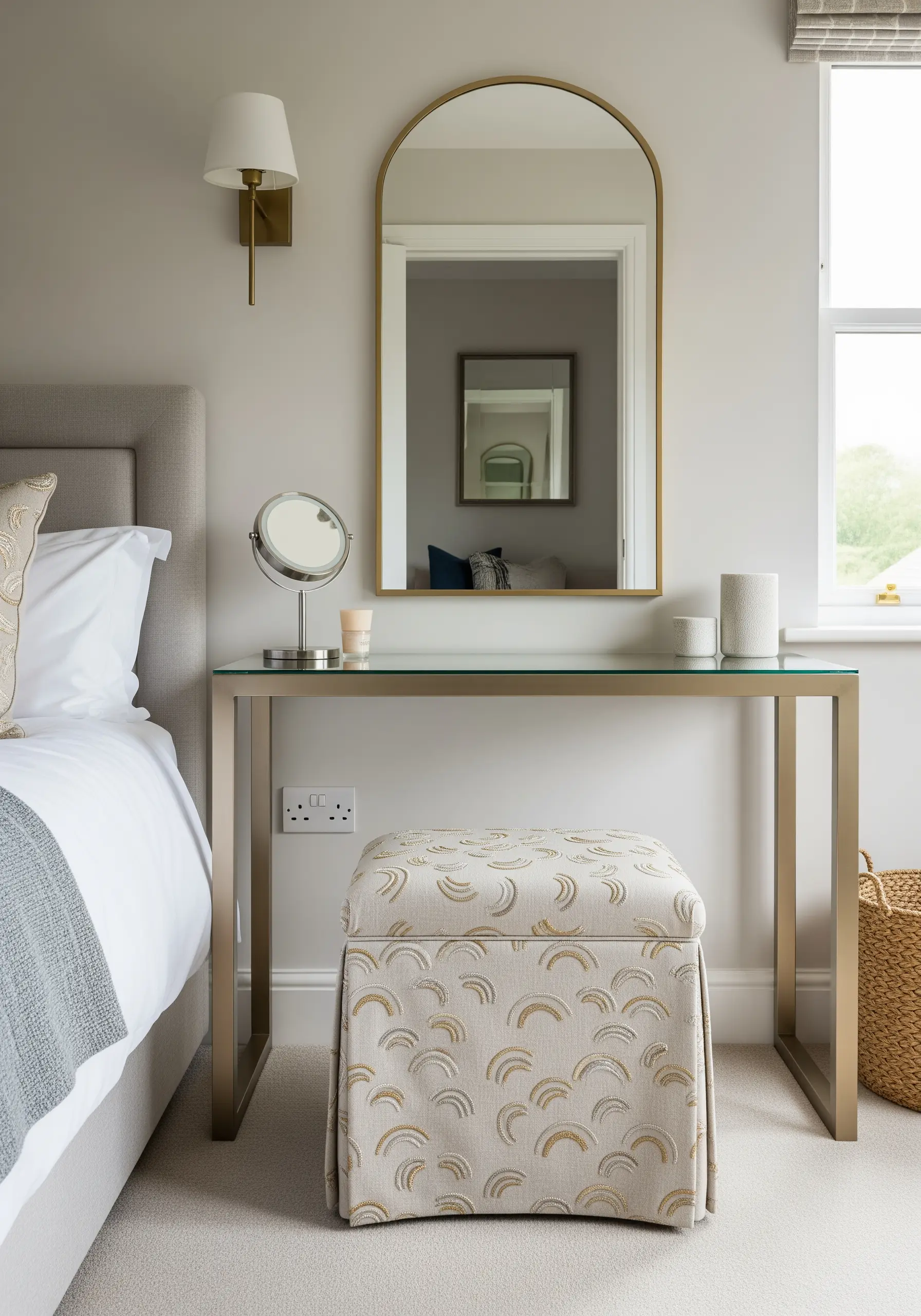 A vanity stool upholstered with fabric featuring a repeating embroidered arc pattern in neutral and gold.