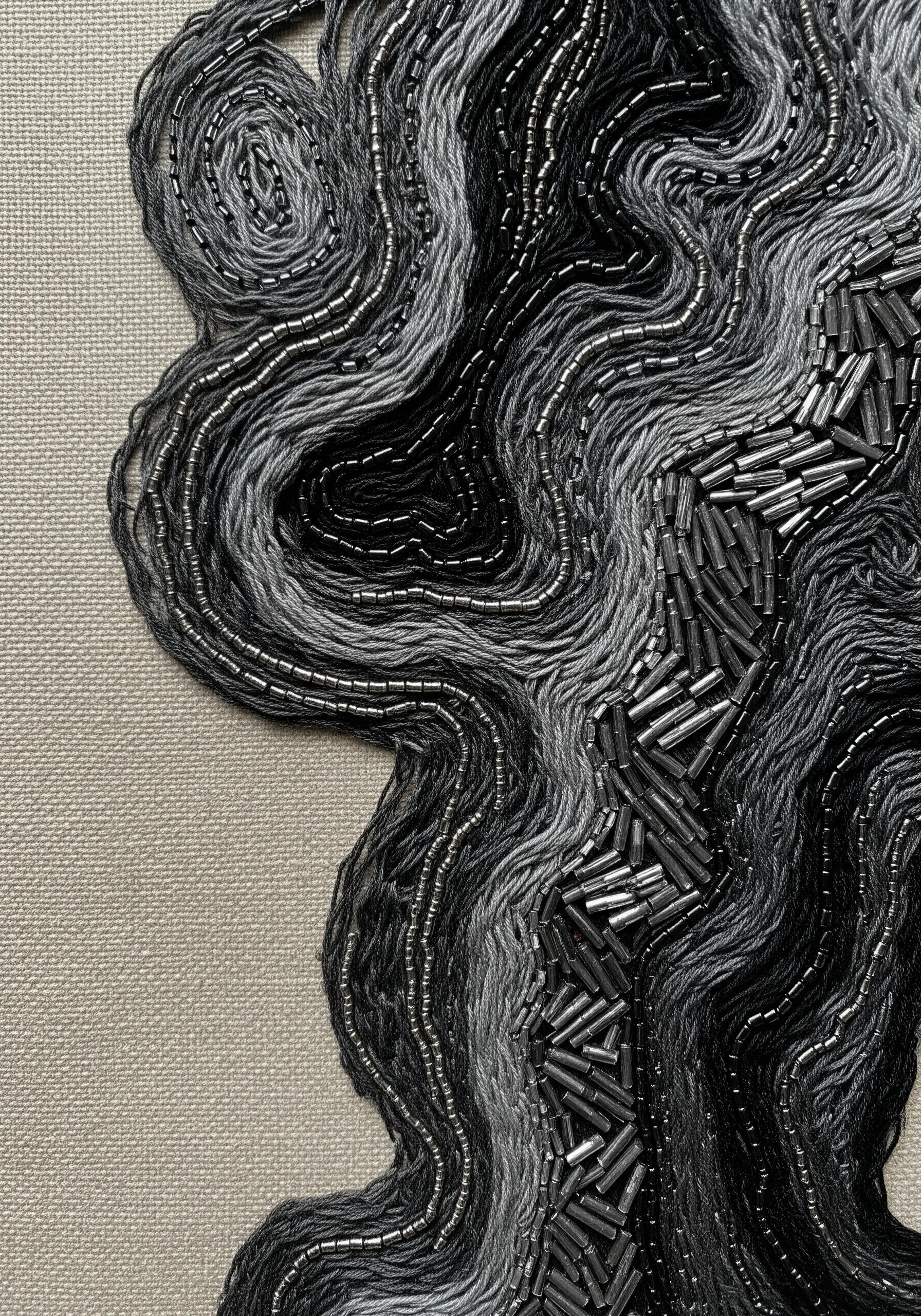 Abstract textural embroidery in black and gray, with flowing lines of thread and bugle beads.