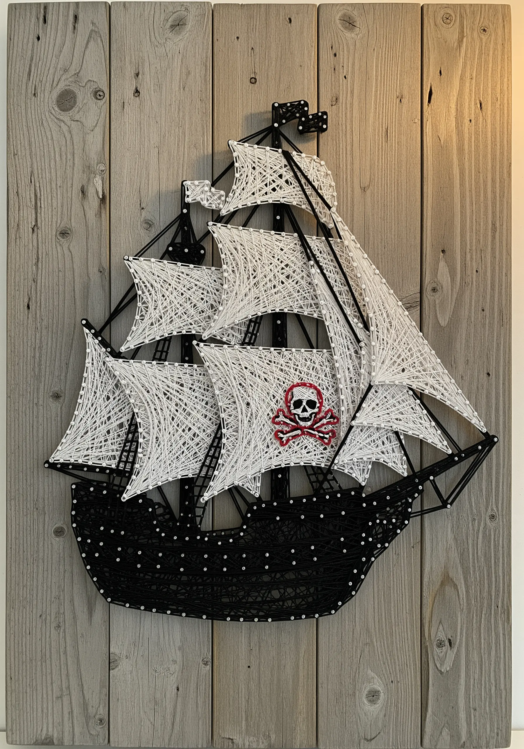 A pirate ship embroidered with a solid black hull and airy, open-stitched white sails.