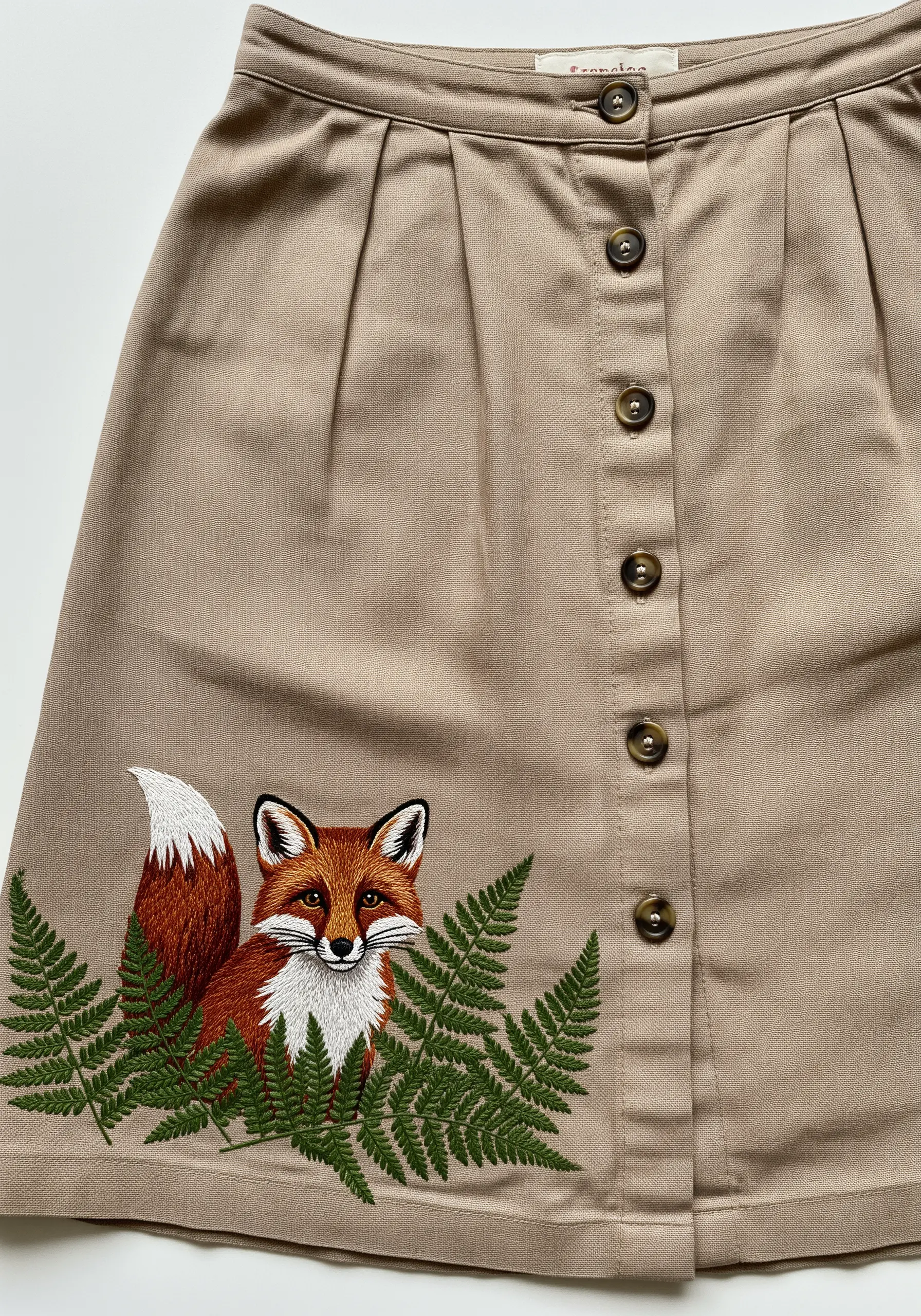 An embroidered fox surrounded by ferns on a button-front khaki skirt.