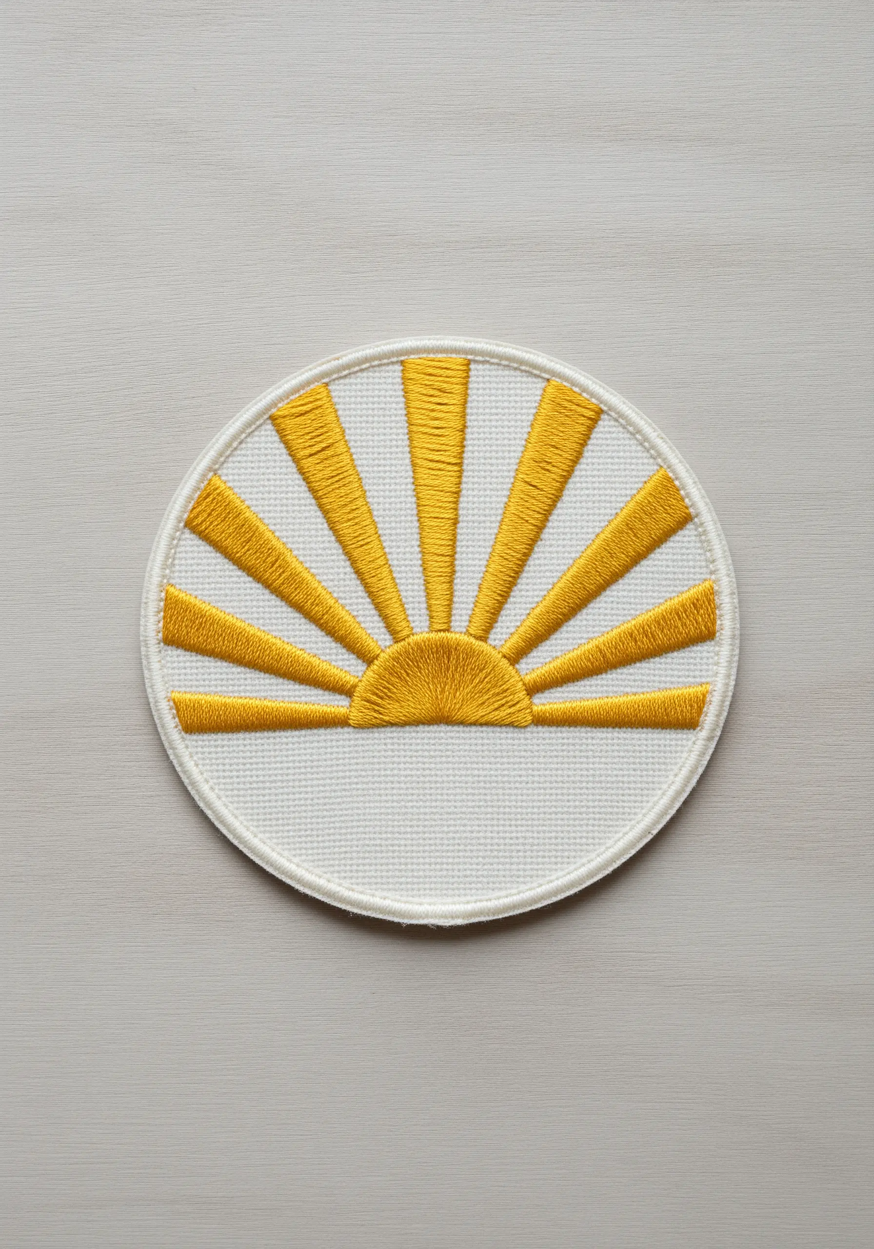 A graphic sunrise patch with yellow satin stitch rays and un-stitched negative space.