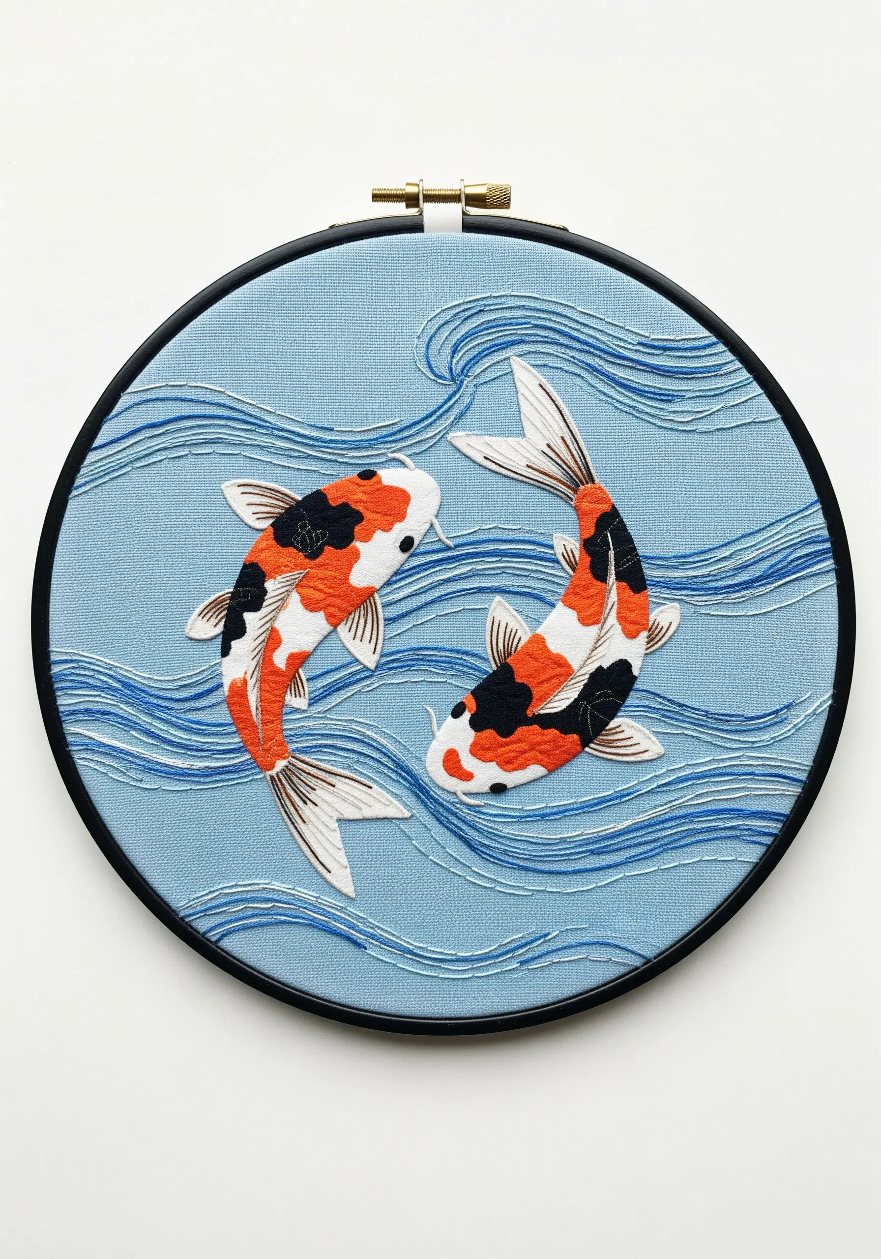 Two koi fish appliquéd on light blue fabric, surrounded by wavy embroidered lines representing water.