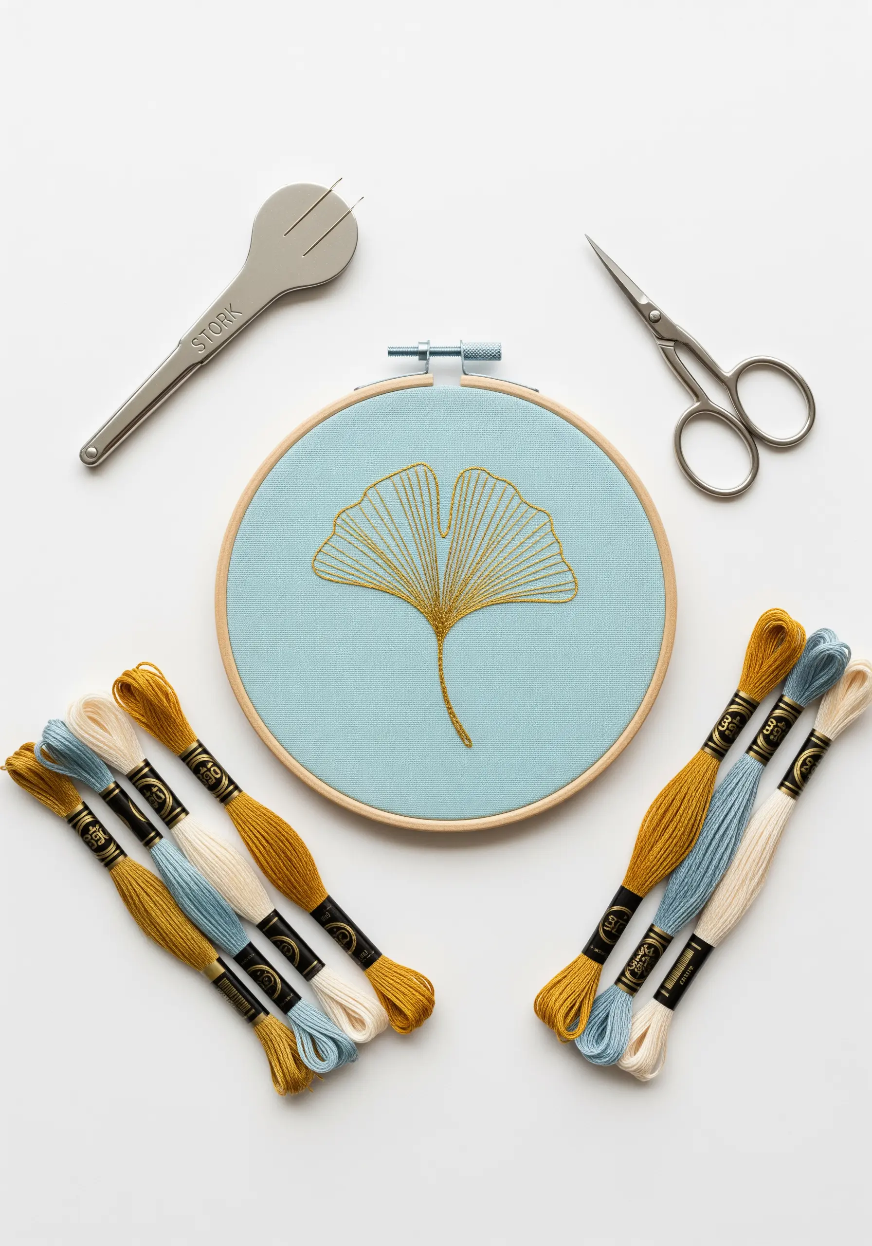 A single ginkgo leaf embroidered in gold thread on a light blue fabric.