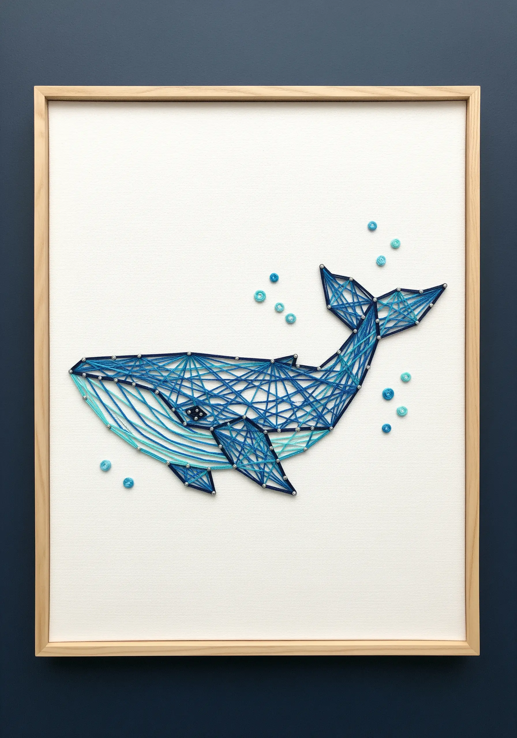 A geometric whale filled with intersecting straight stitches in various shades of blue.