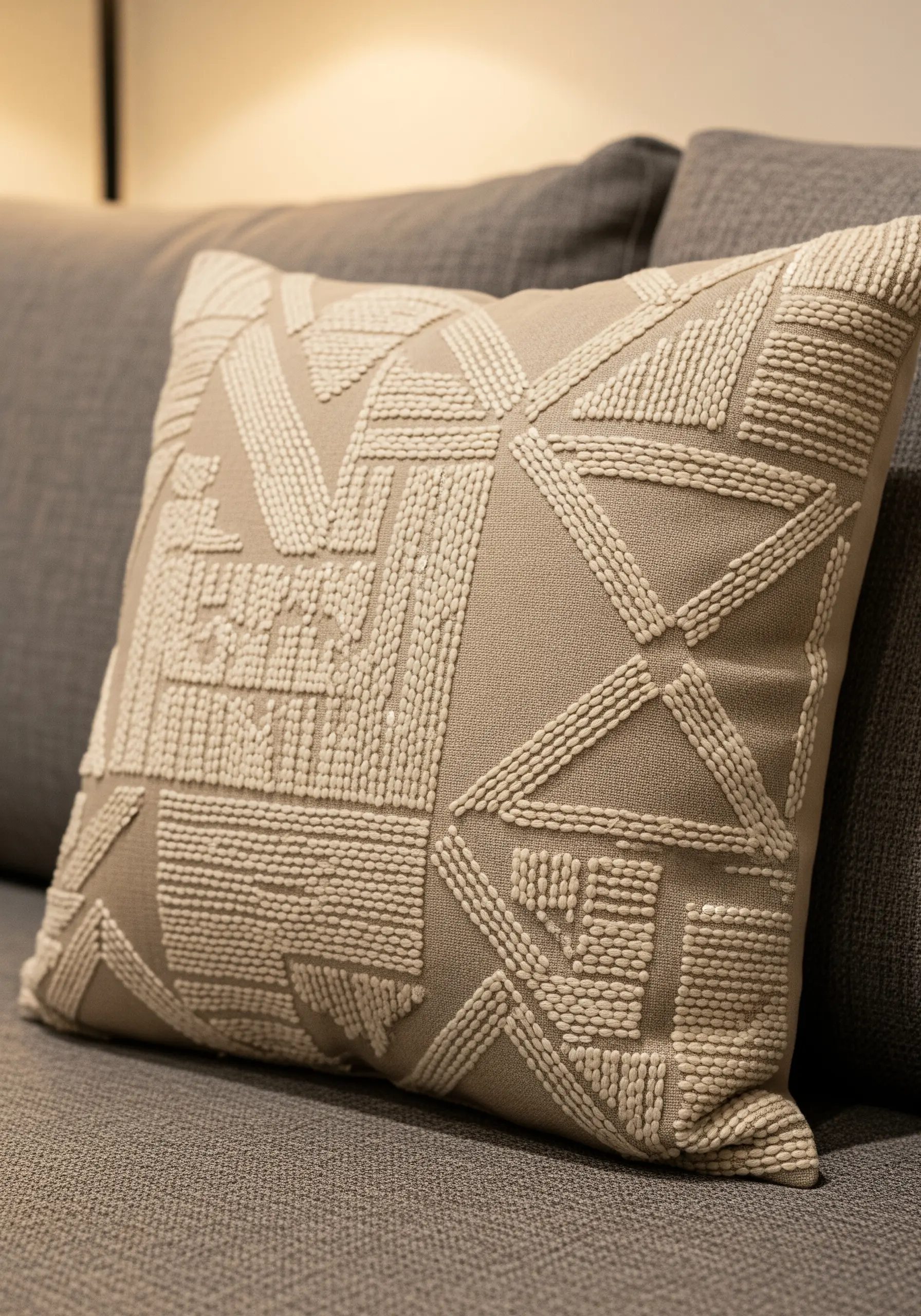 Close-up of a beige cushion with an abstract geometric pattern in cream seed stitches.