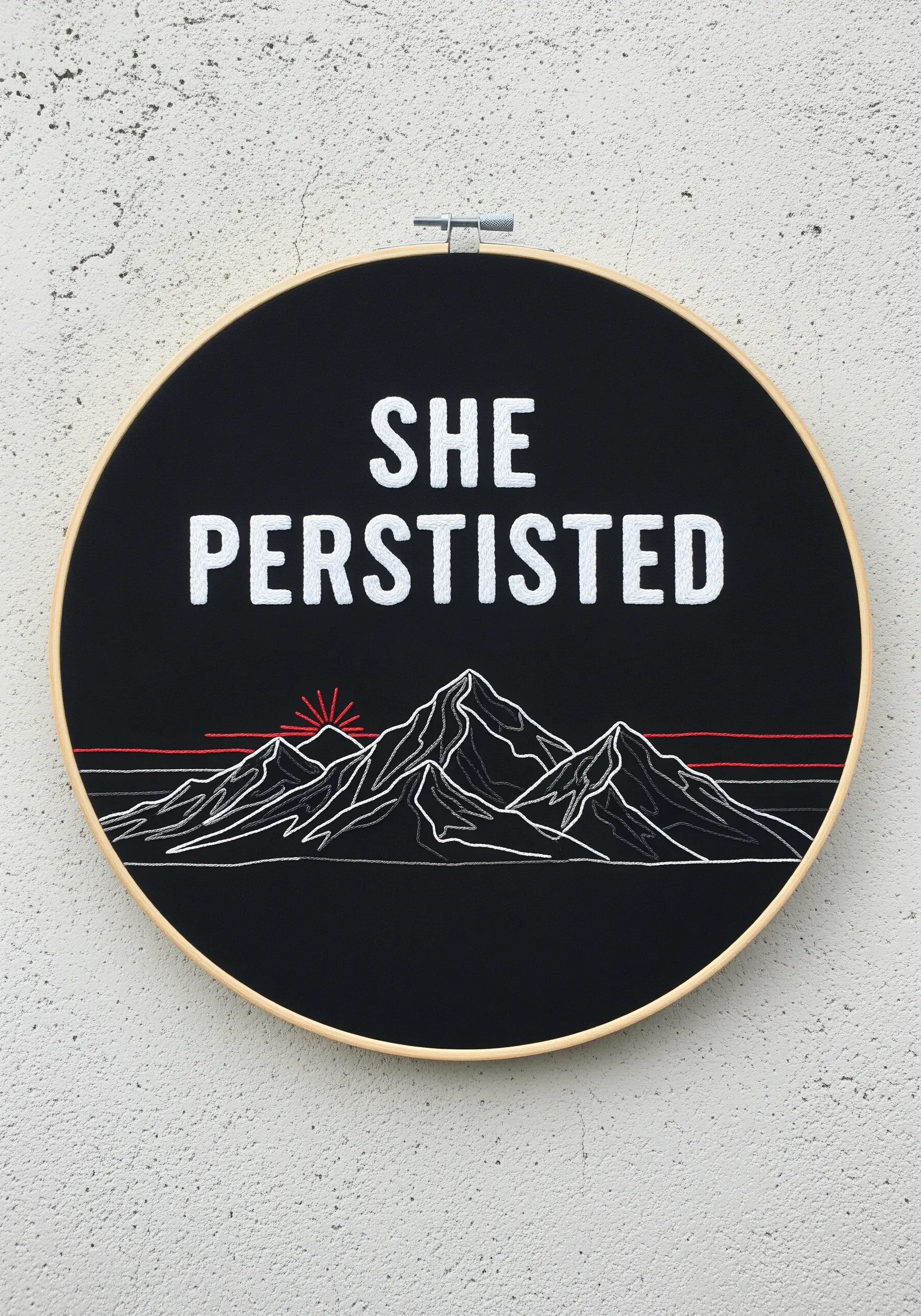 Embroidered mountain range with “She Persisted” quote on black fabric with a red accent line.