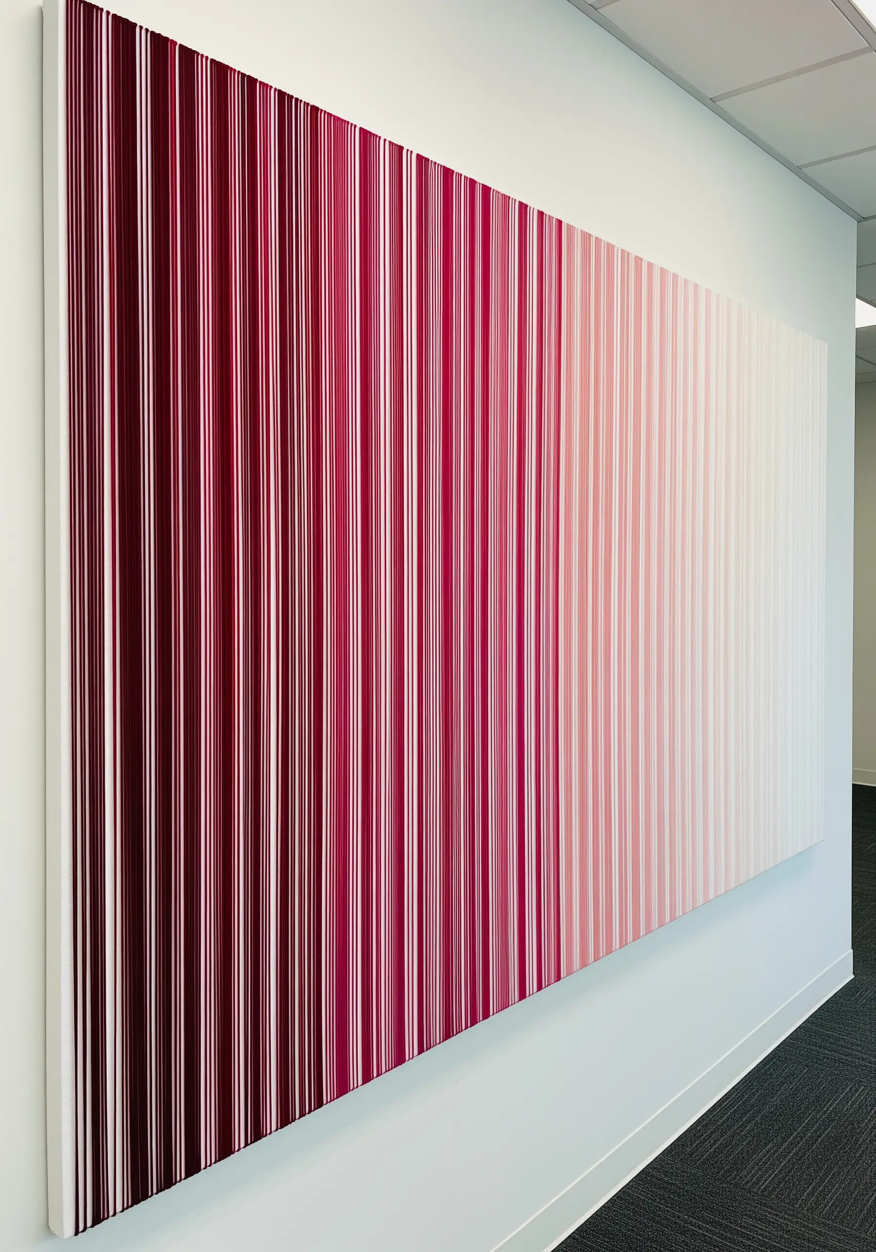 Large canvas covered in vertical thread strands fading from deep red to pale pink