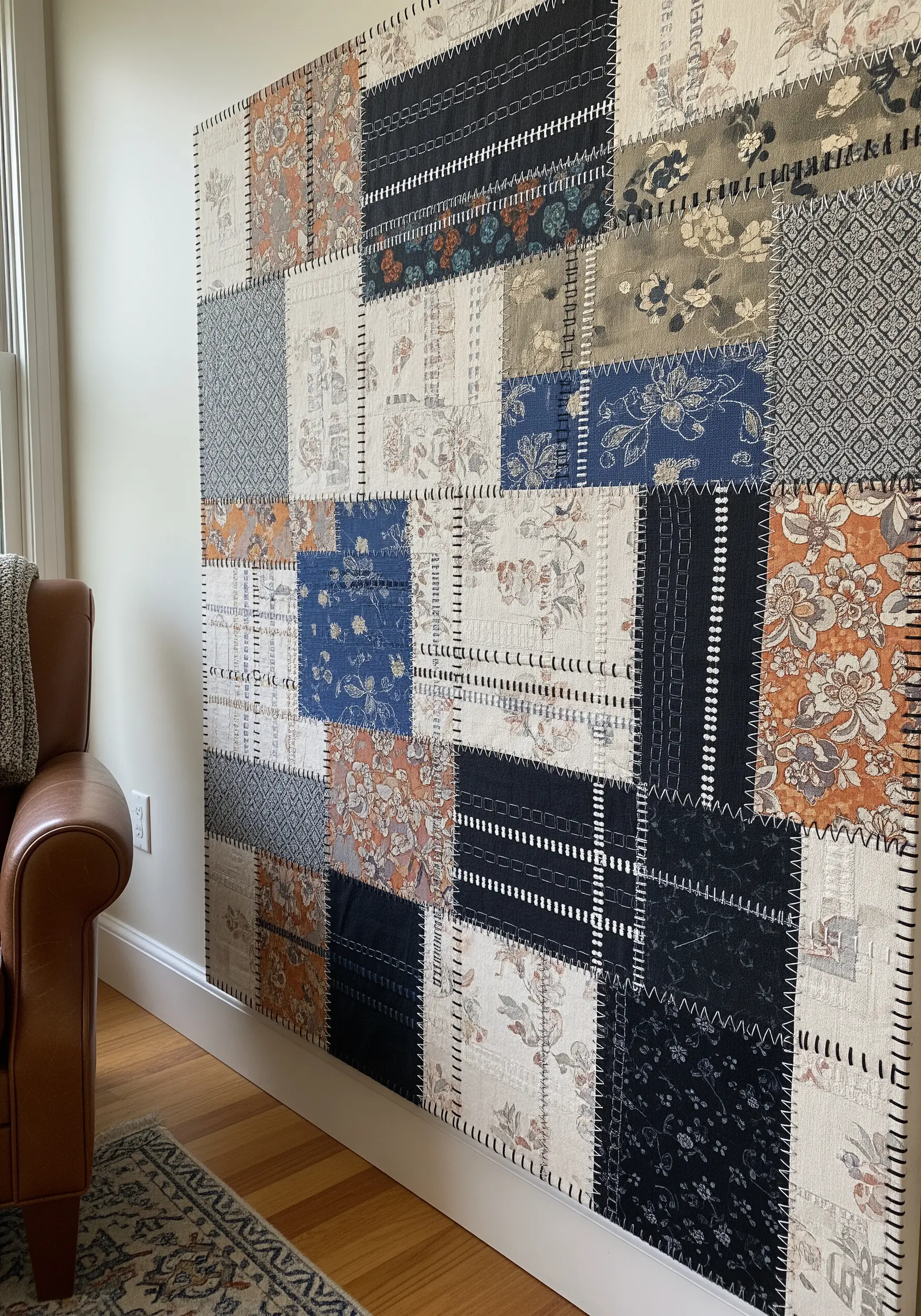 Wall hanging made of various patterned fabric squares joined by visible black stitching