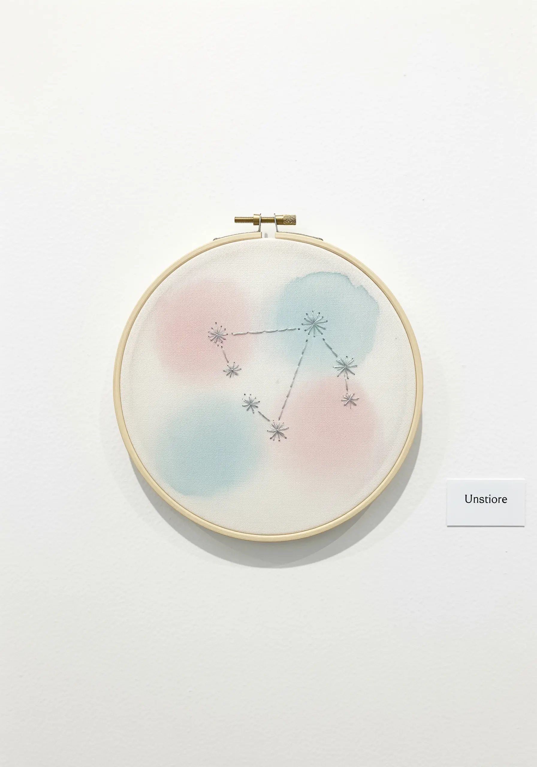 Embroidered constellation over soft watercolor circles in a wooden hoop.
