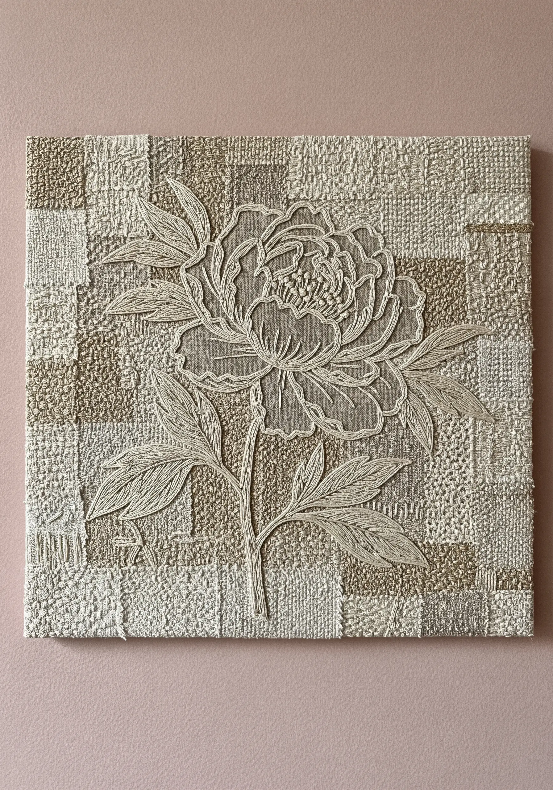 A monochrome line art peony embroidered onto a background of woven neutral fabric strips.