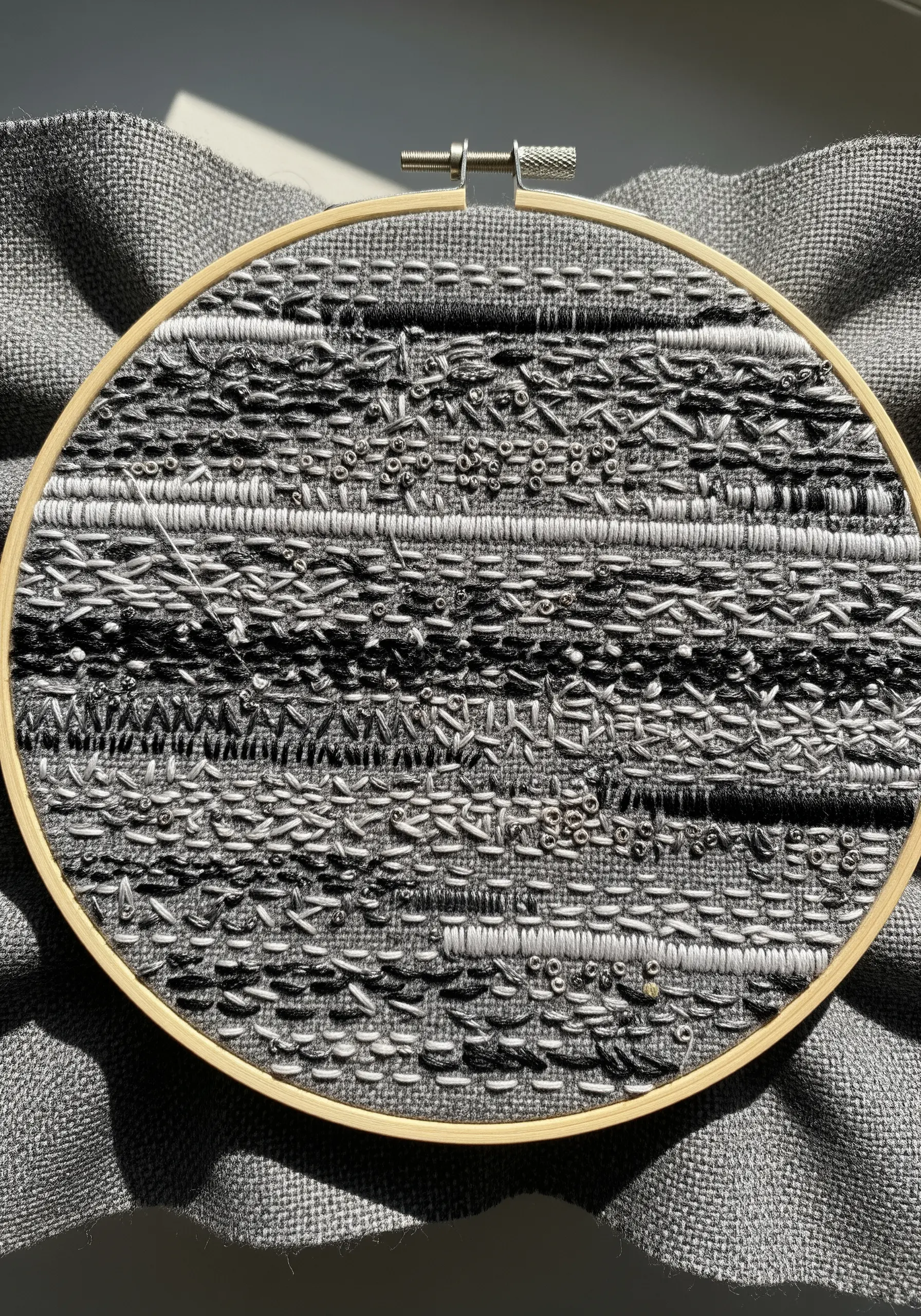 A highly textured abstract monochrome embroidery with mixed threads and beads.