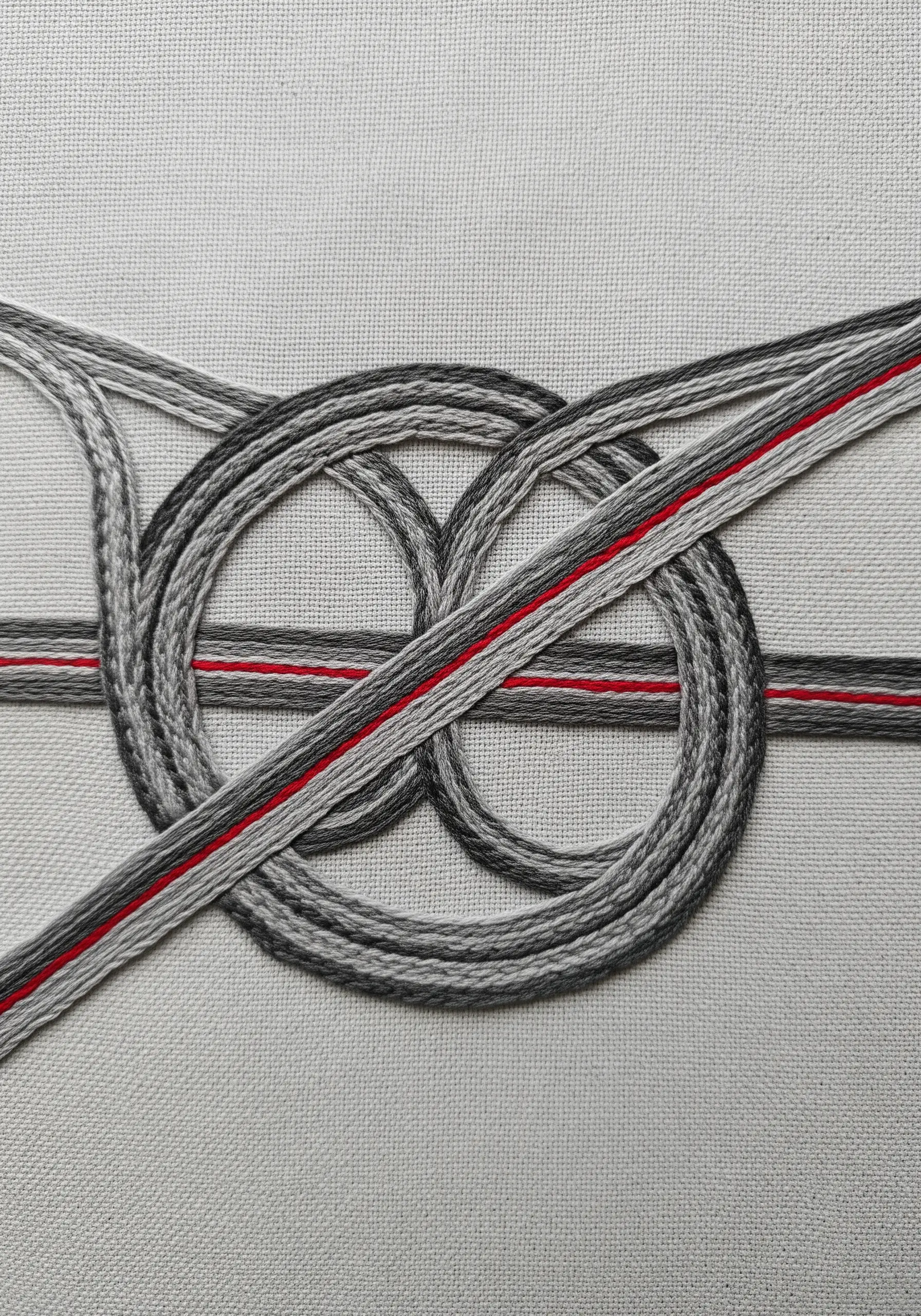 An abstract embroidered highway interchange in gray, with one red accent line.
