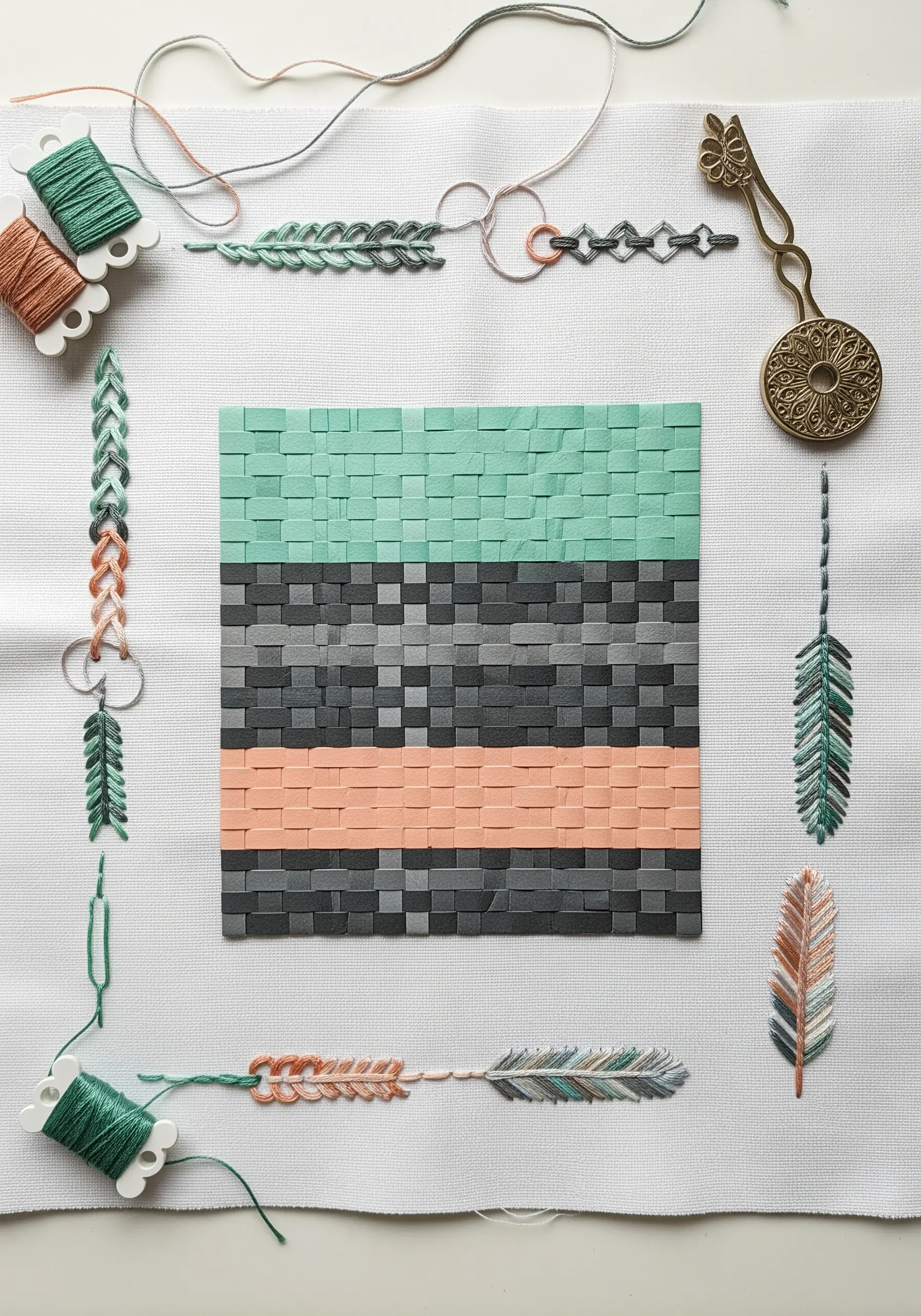 A central woven paper square in mint, grey, and coral, framed by delicate stitch samplers.