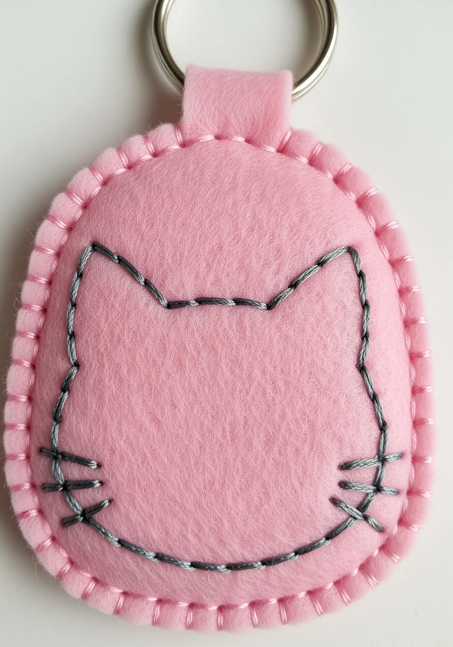 Simple cat outline in whipped backstitch on a pink felt keychain