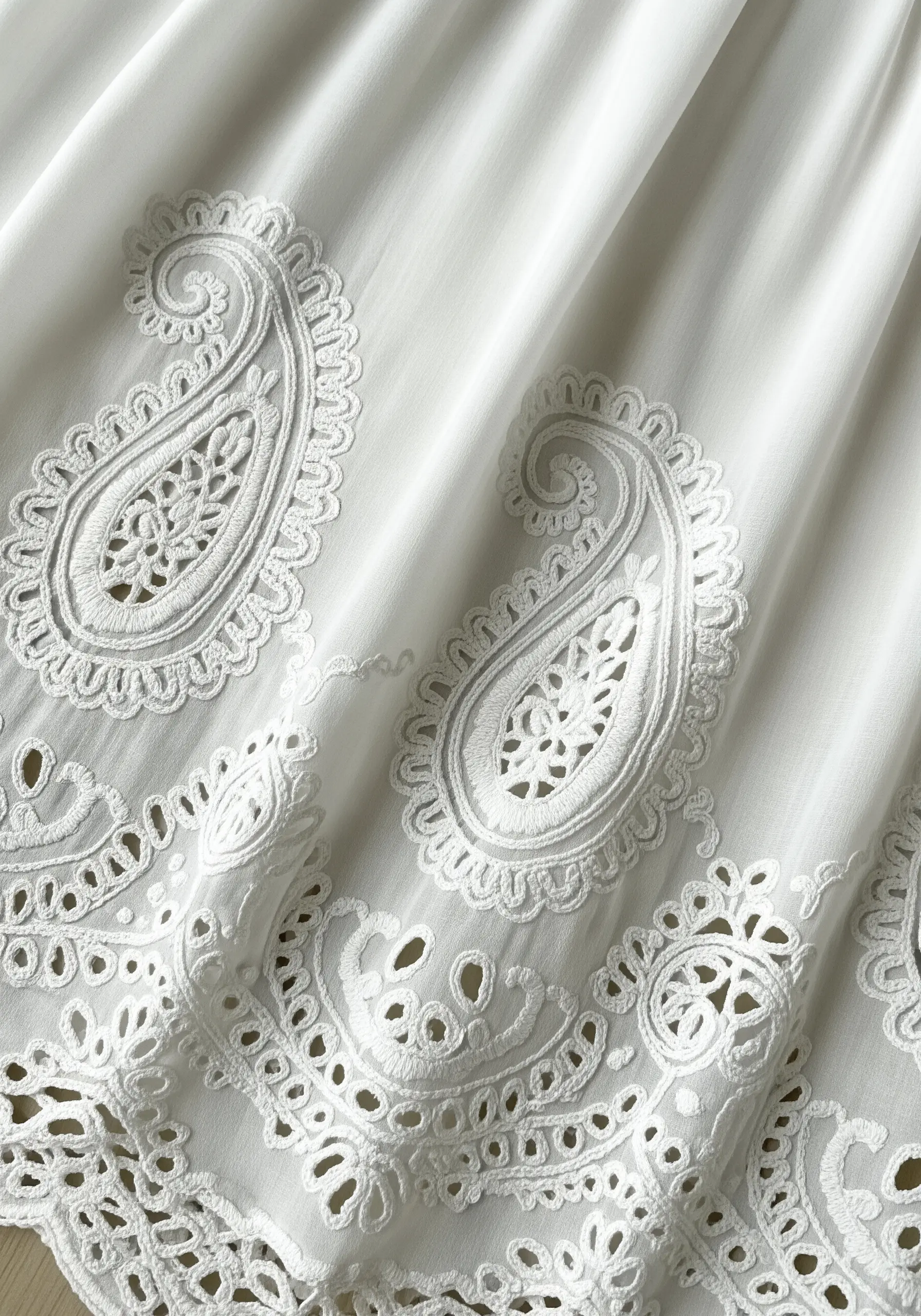 White fabric with intricate white paisley cutwork embroidery
