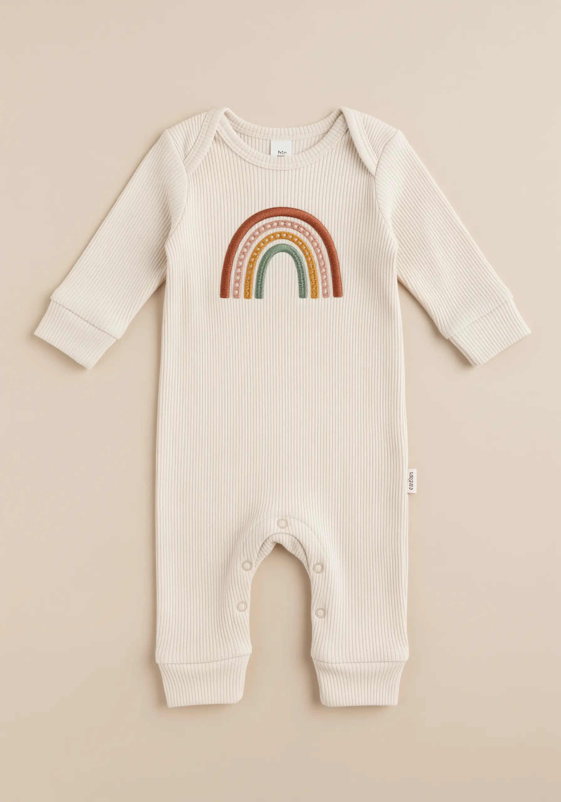 An embroidered rainbow with earthy tones and varied textures on a ribbed onesie.