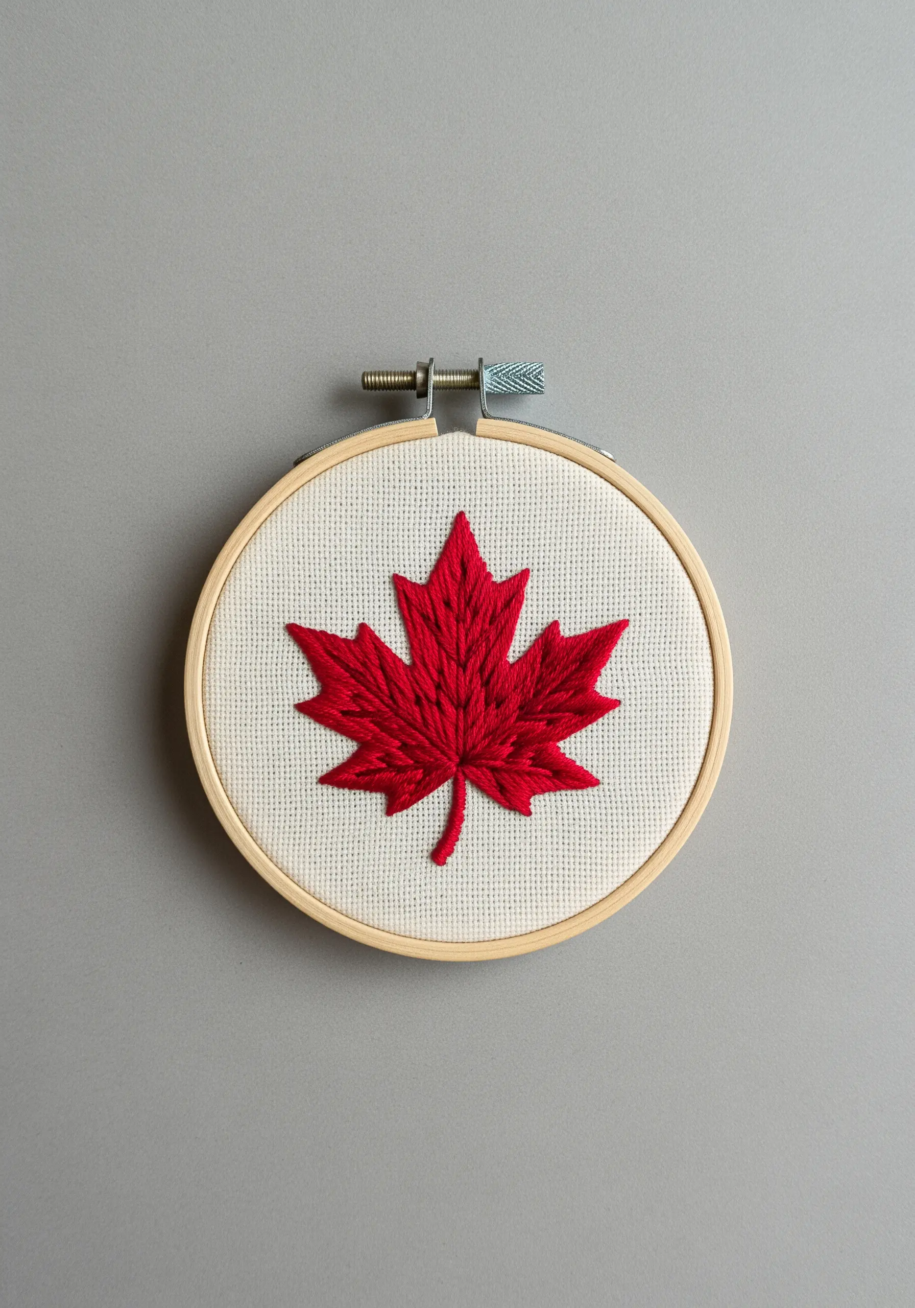 A vibrant red maple leaf with clean, sharp satin stitch edges.