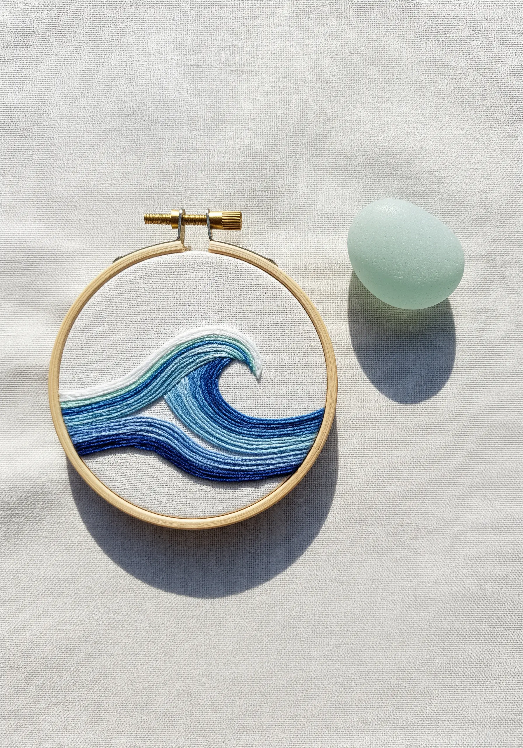 Embroidered ocean wave with blended blue threads in a small hoop.
