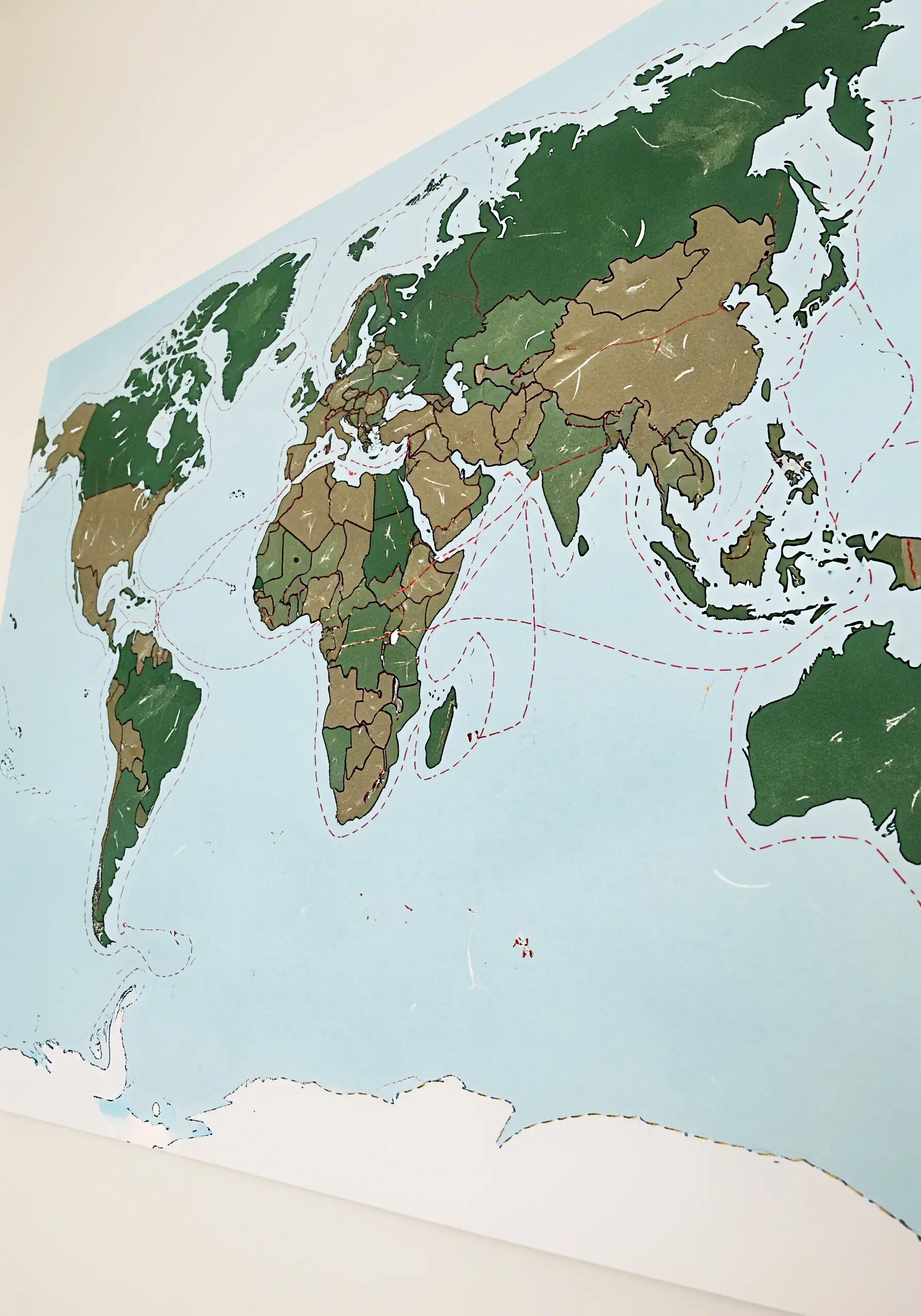 A world map with a journey traced across continents and oceans using a red dashed stitch.