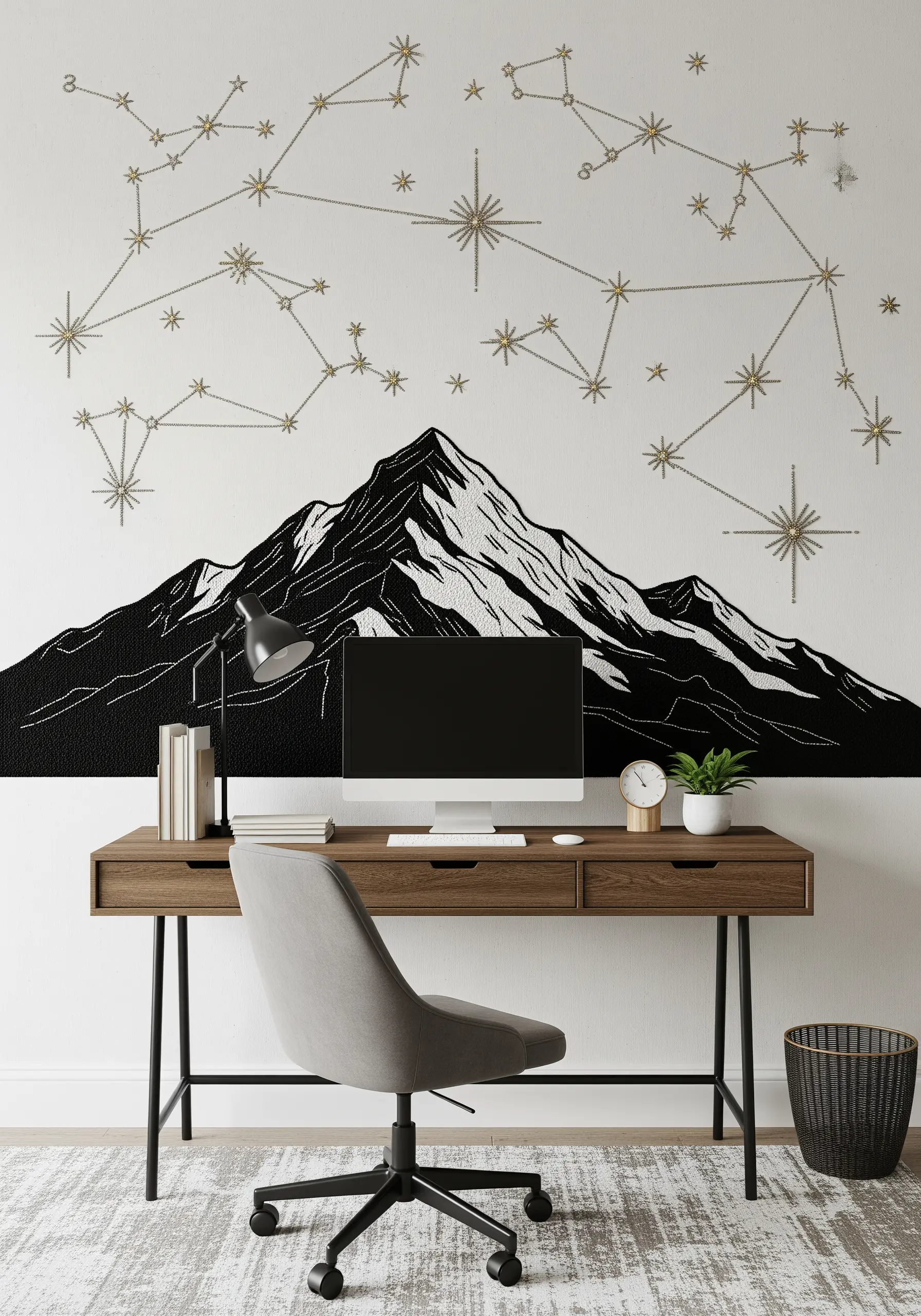 A wall mural behind a desk with a graphic black-and-white embroidered mountain below gold constellations.