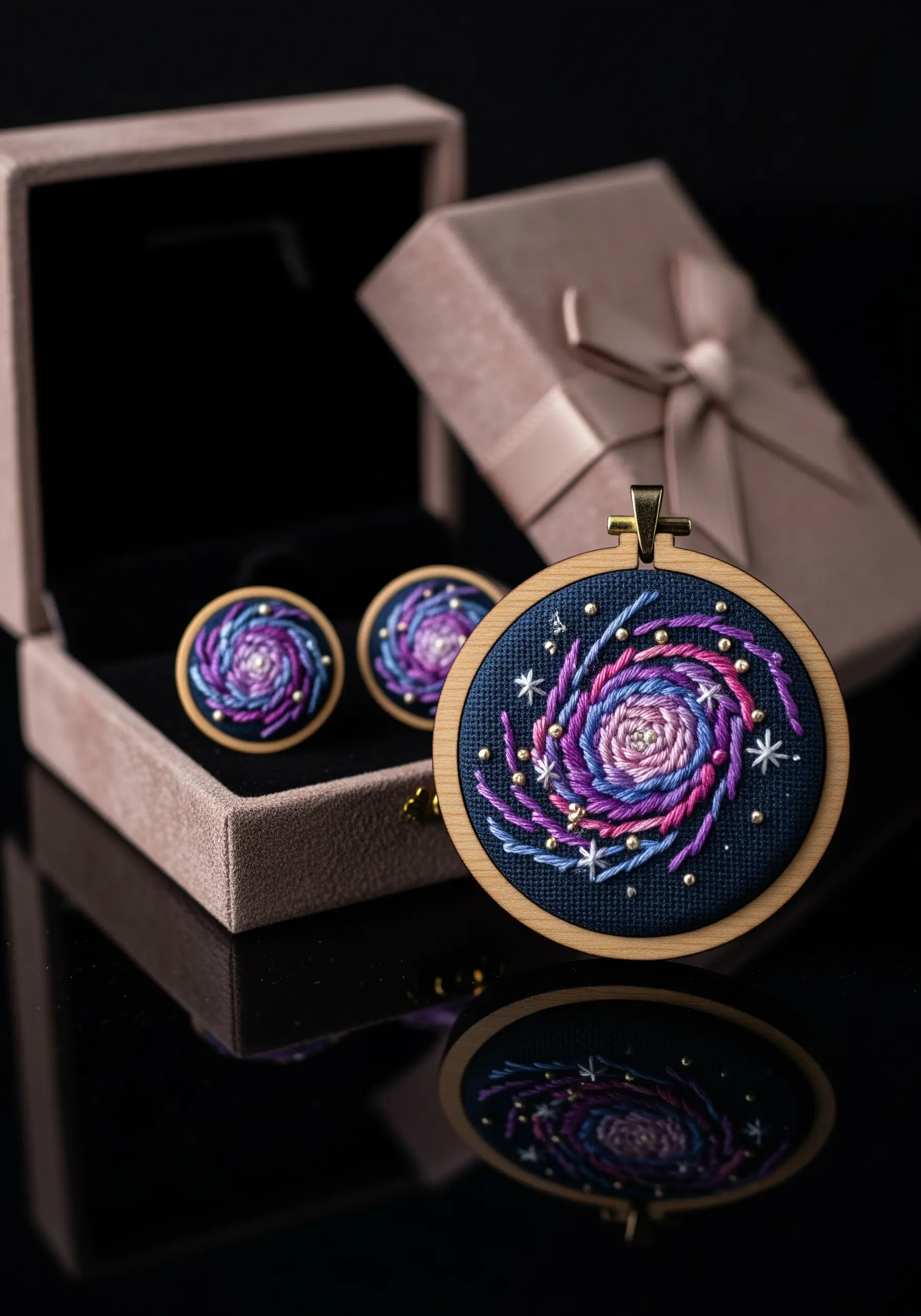 An embroidered pendant and matching earrings depicting a purple and blue galaxy in a jewelry box.