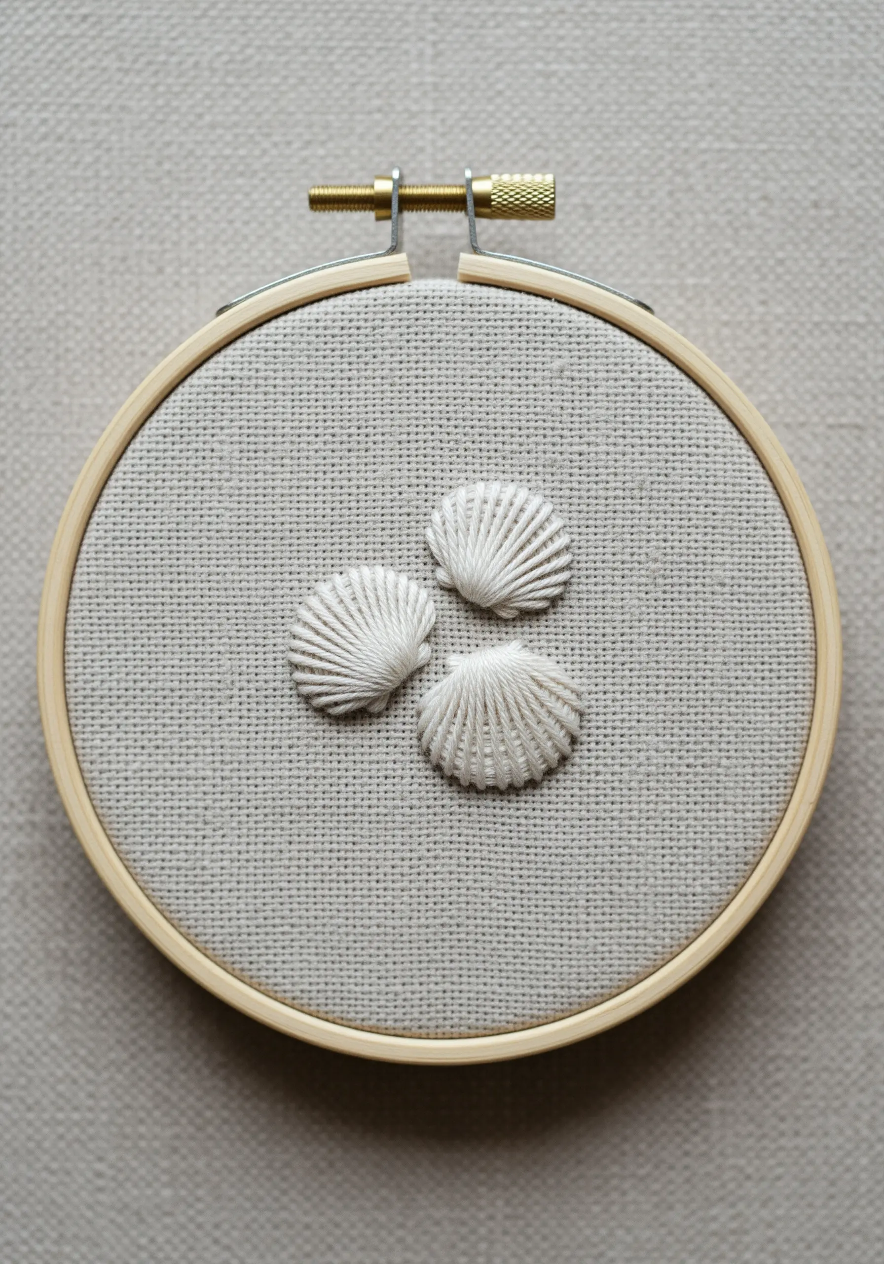 Three-dimensional embroidered seashells on neutral linen fabric.