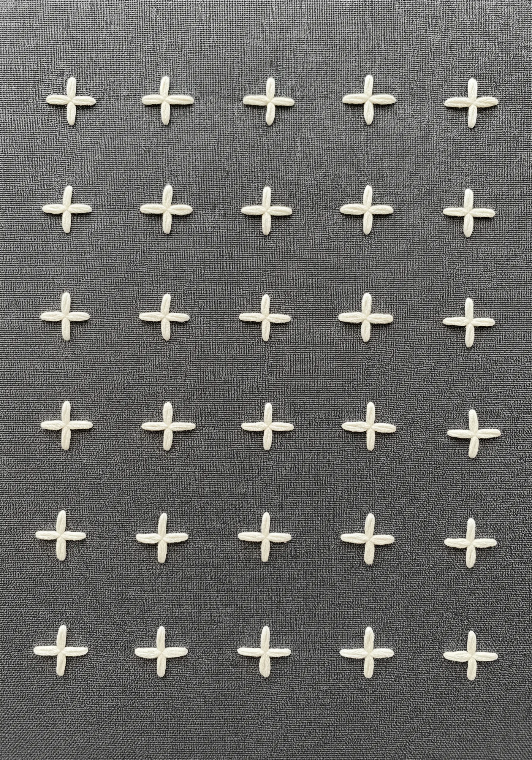 A grid of small, evenly spaced plus-sign stitches embroidered in white on dark gray fabric.