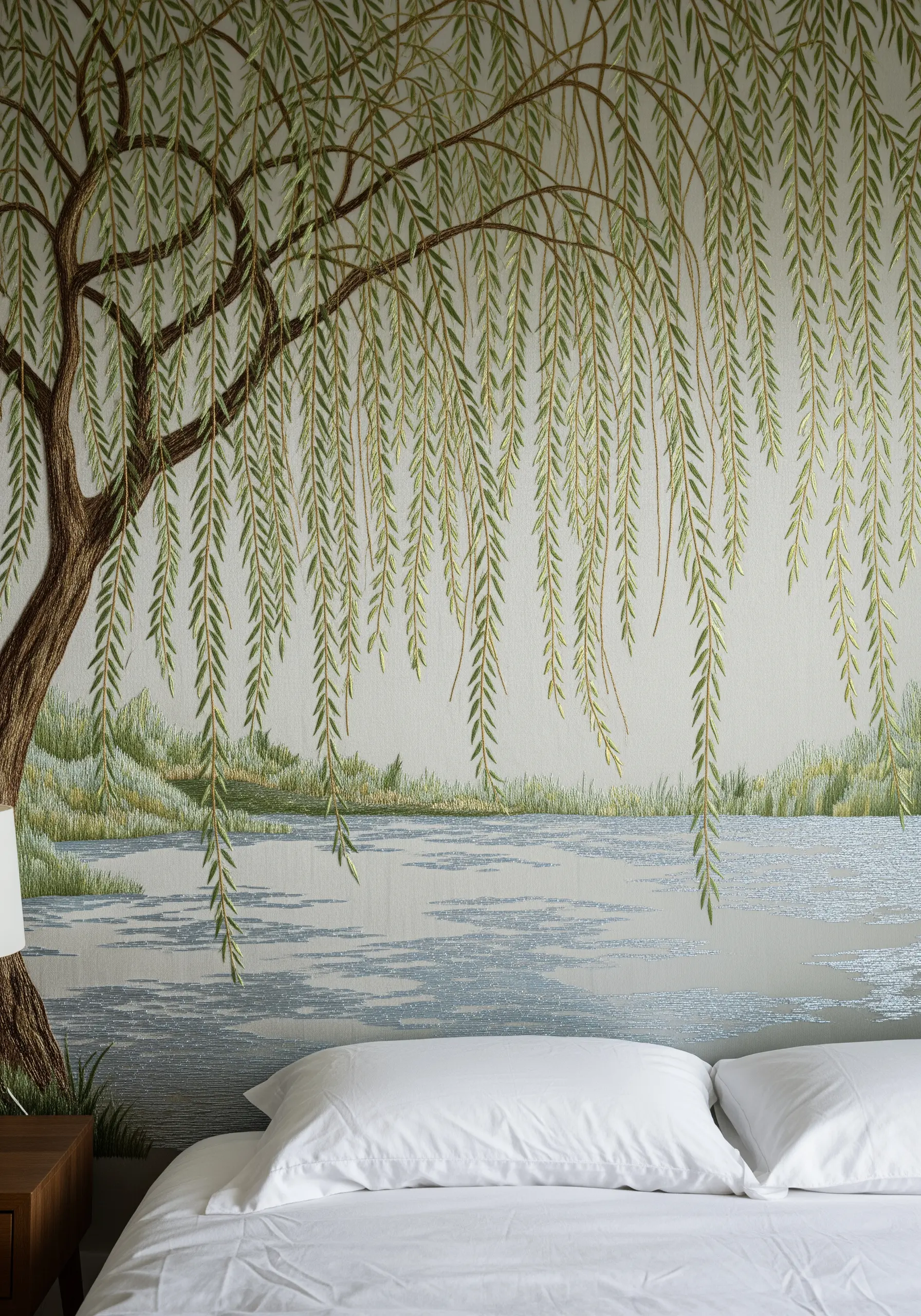 A serene bedroom with an embroidery mural of a weeping willow tree over a calm lake.