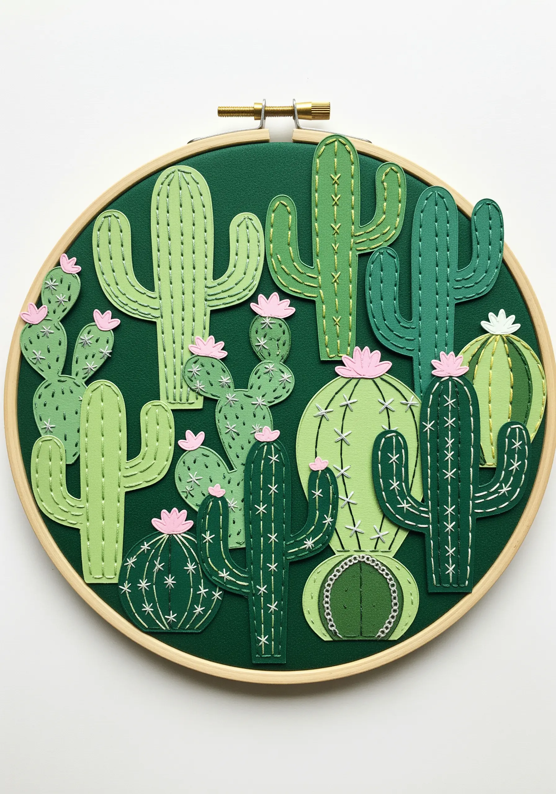 A collection of green paper cactus shapes stitched onto dark green fabric in an embroidery hoop.