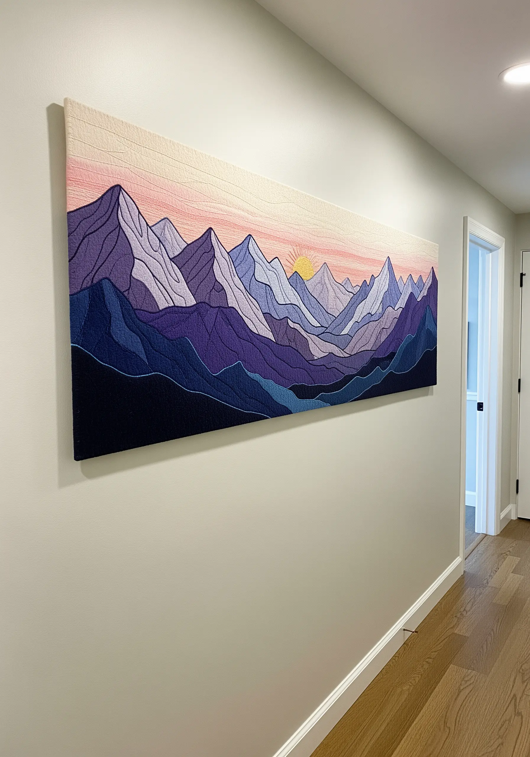 A long, panoramic embroidery of a purple mountain range with graphic outlines and a pink sunset sky.