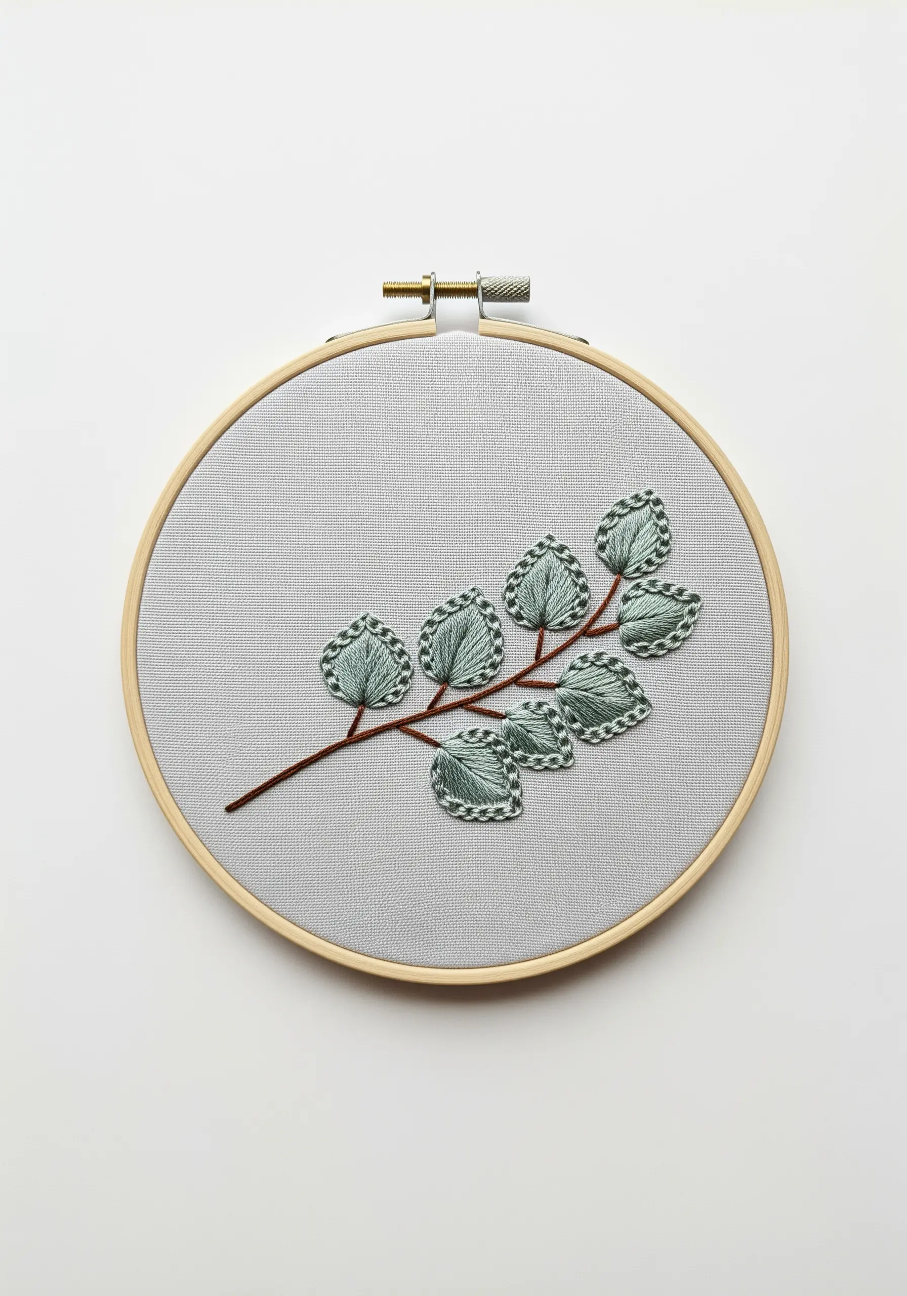 A branch of embroidered eucalyptus leaves with decorative blanket stitch borders.
