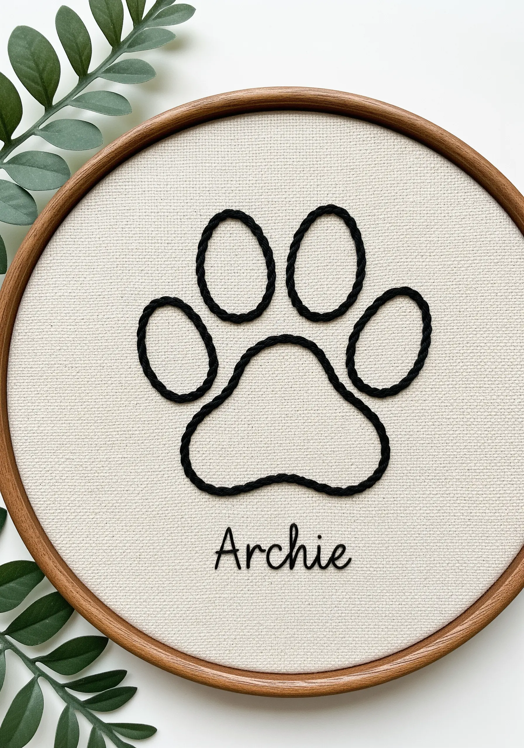 A bold, black embroidered paw print with the name 'Archie' stitched underneath.