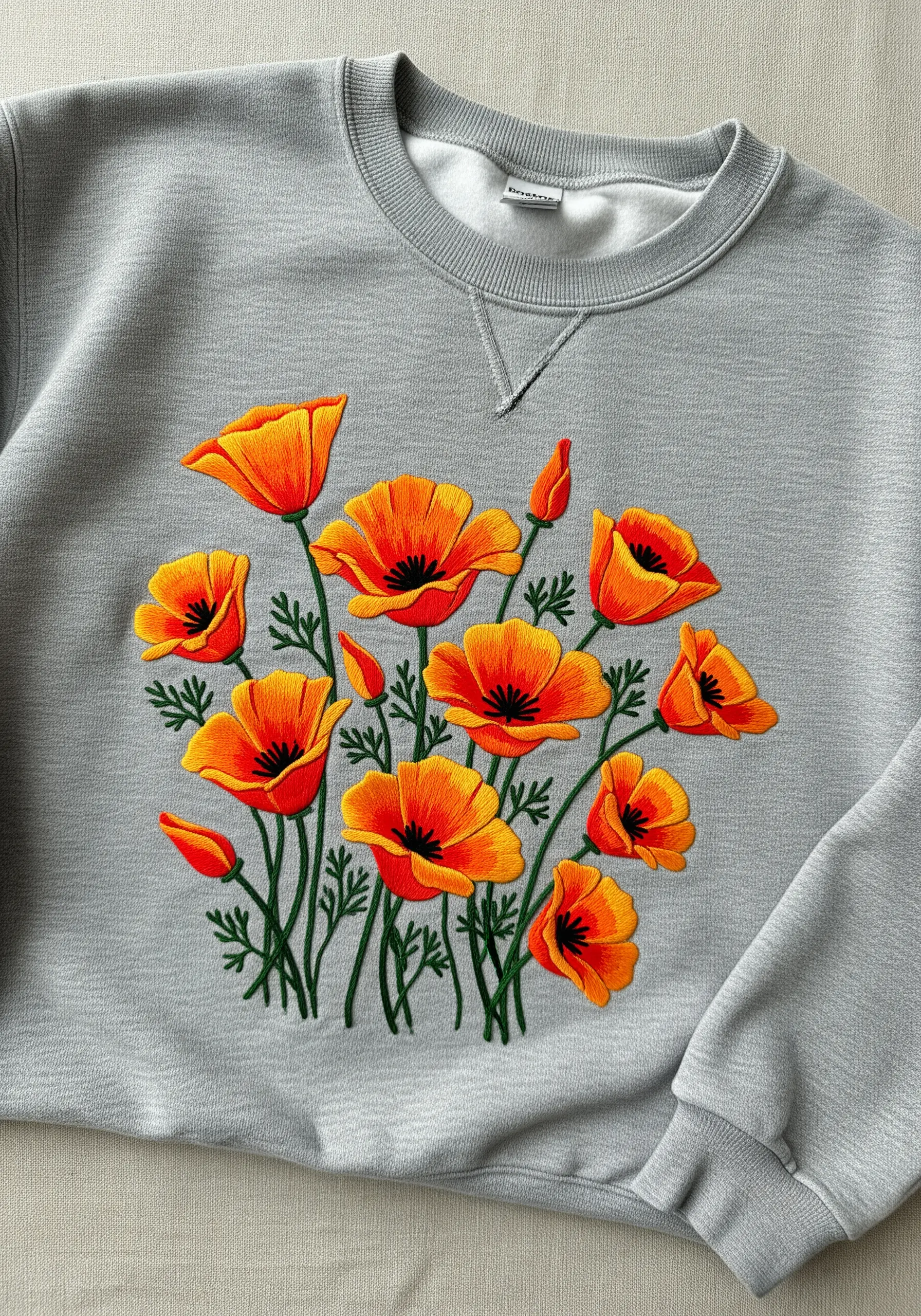 A vibrant bouquet of orange and yellow California poppies embroidered on a grey sweatshirt.
