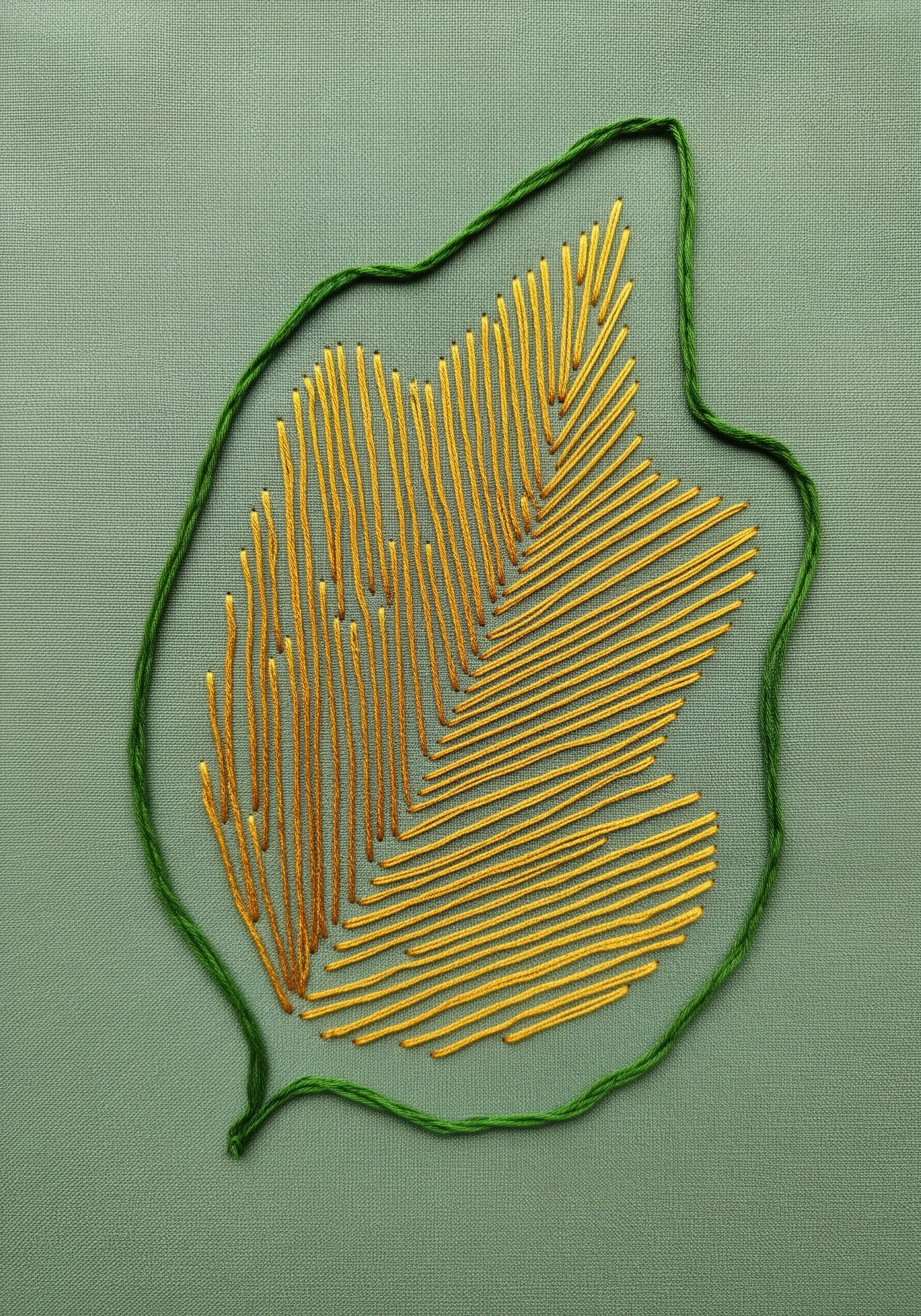 A leaf motif defined by a green outline and filled with spaced-out vertical gold stitches.