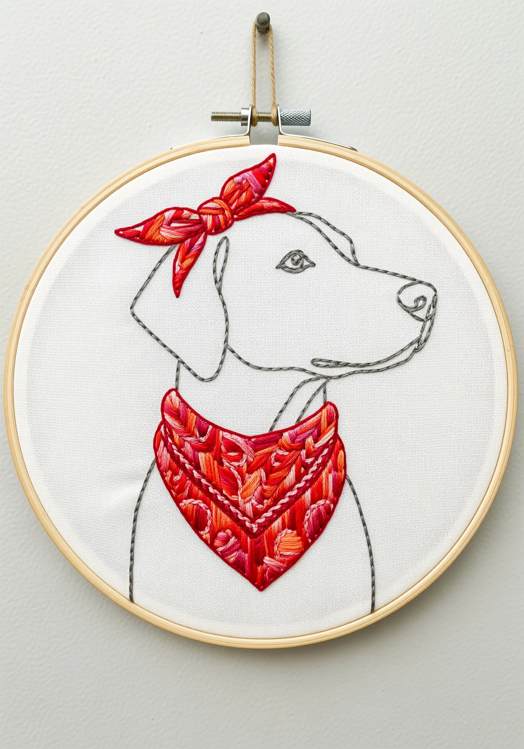 Line art dog wearing a bandana stitched with red and pink variegated thread.