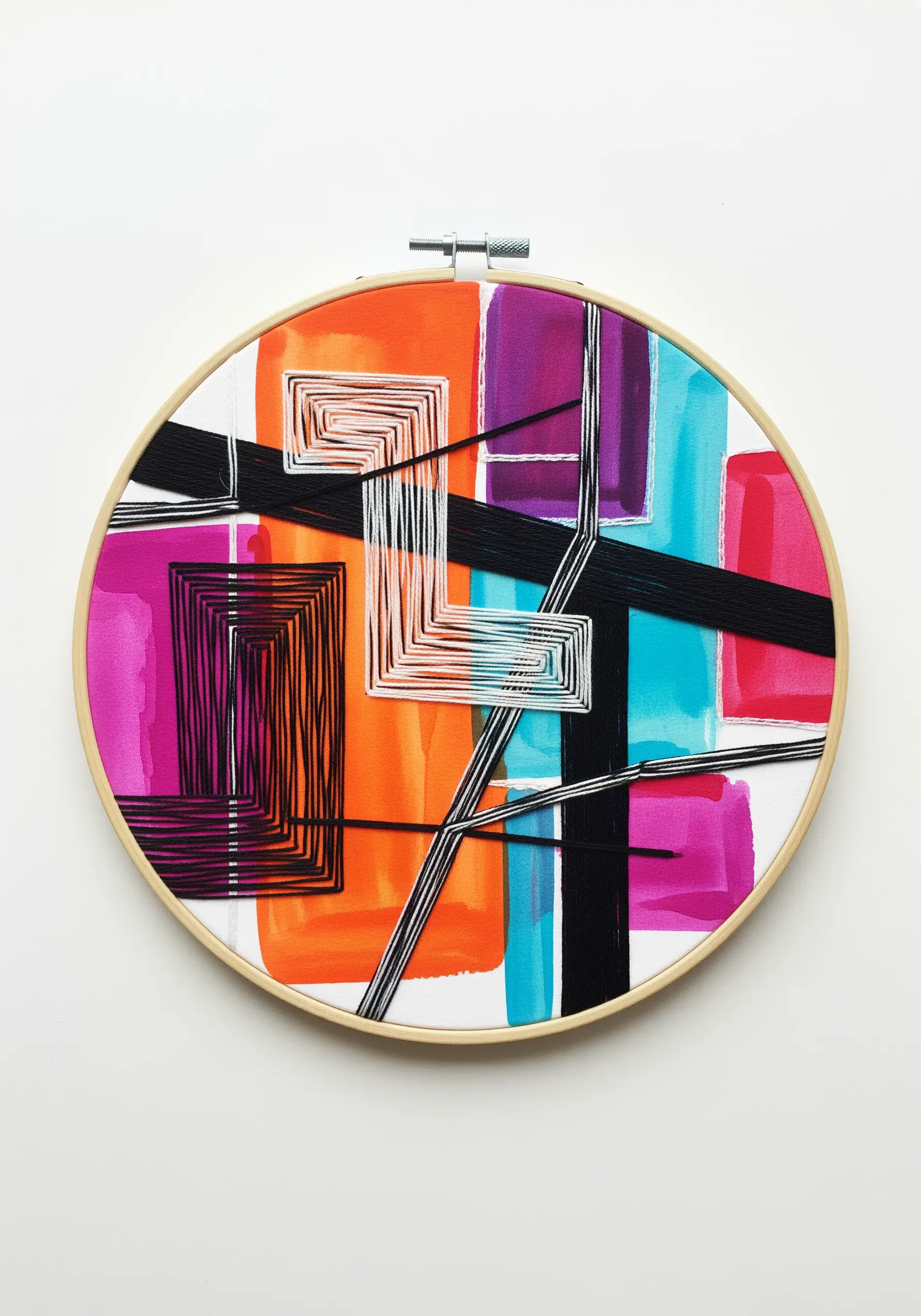 An embroidery hoop with an abstract painting, with black and white thread art stitched on top.