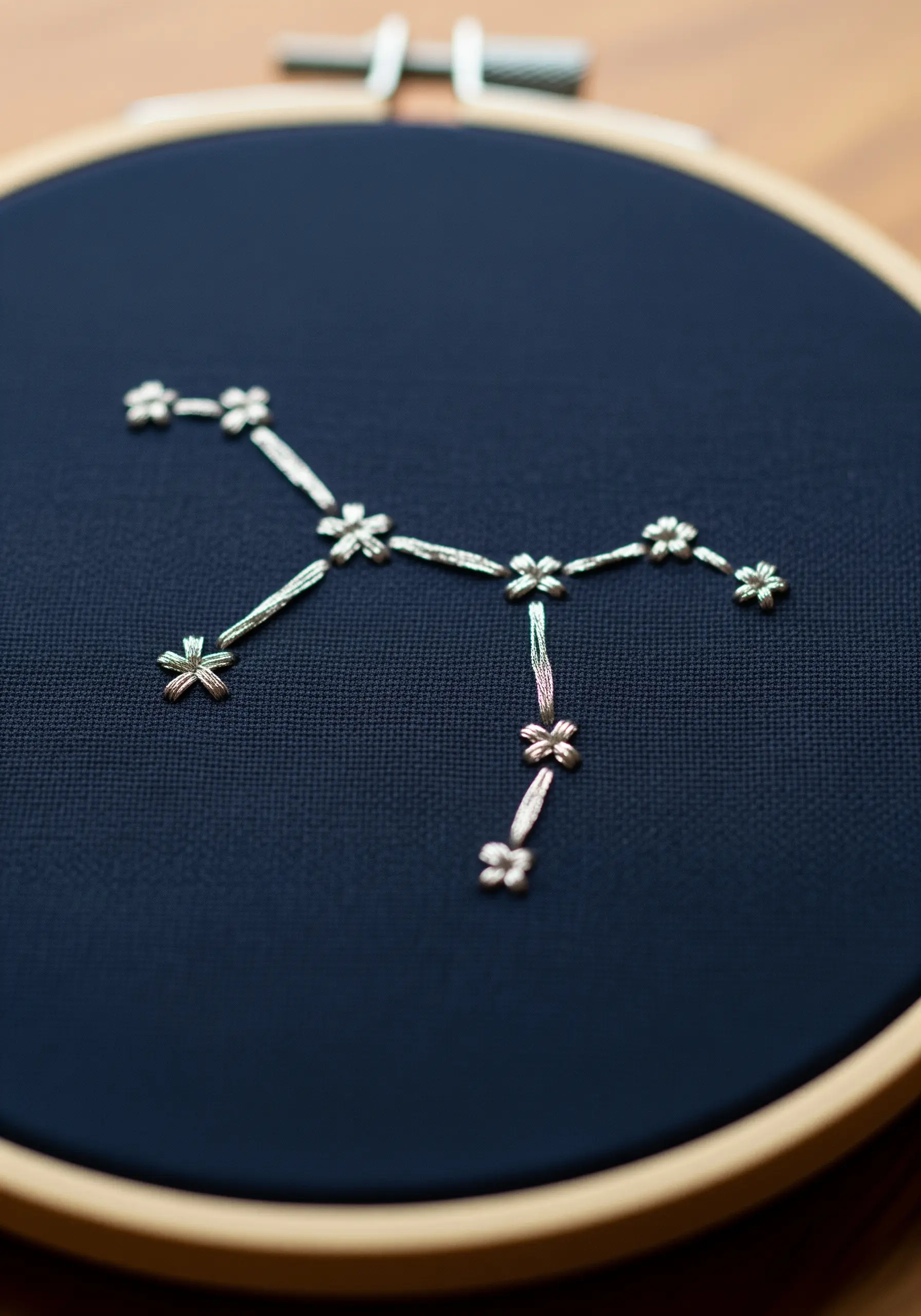 A constellation stitched in silver metallic thread on navy fabric.