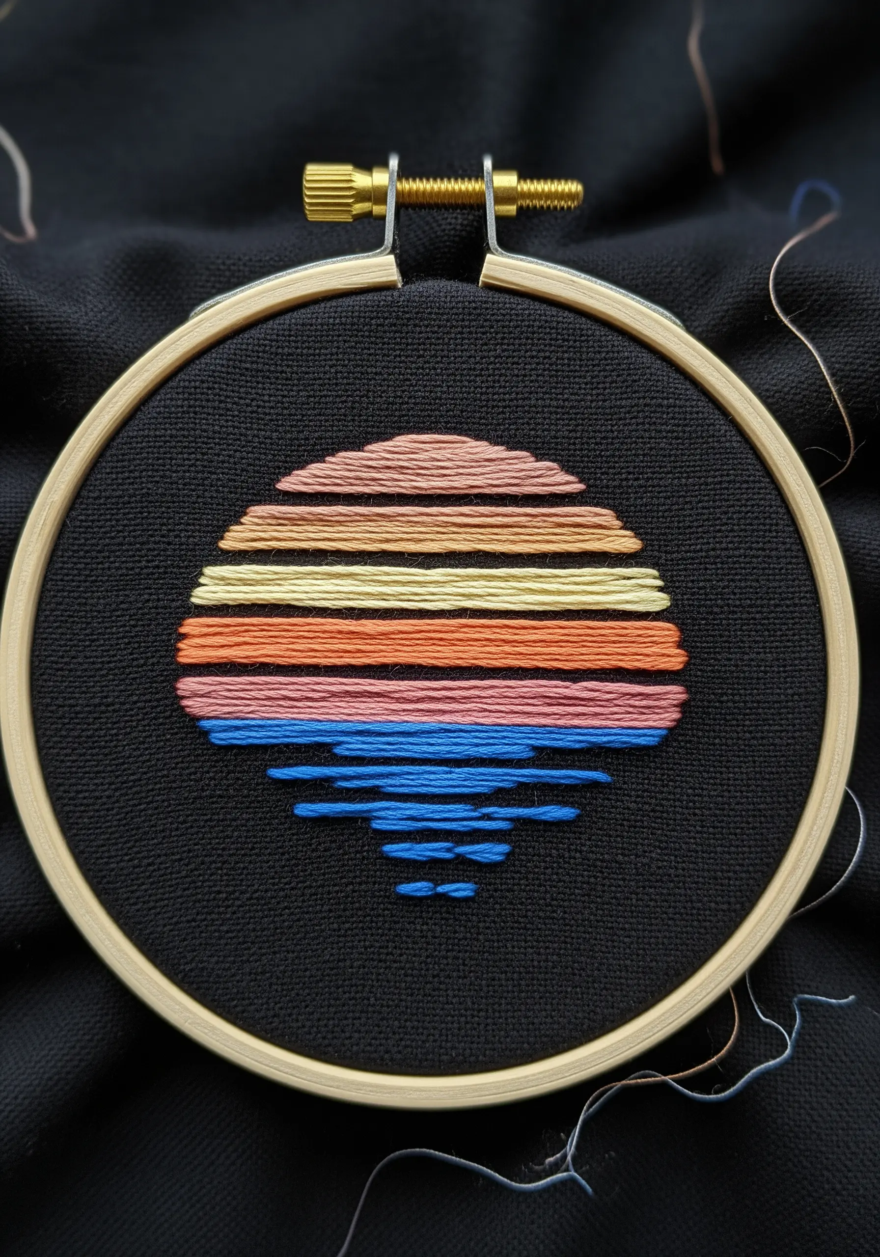 A vibrant, striped sunset embroidered on black fabric.