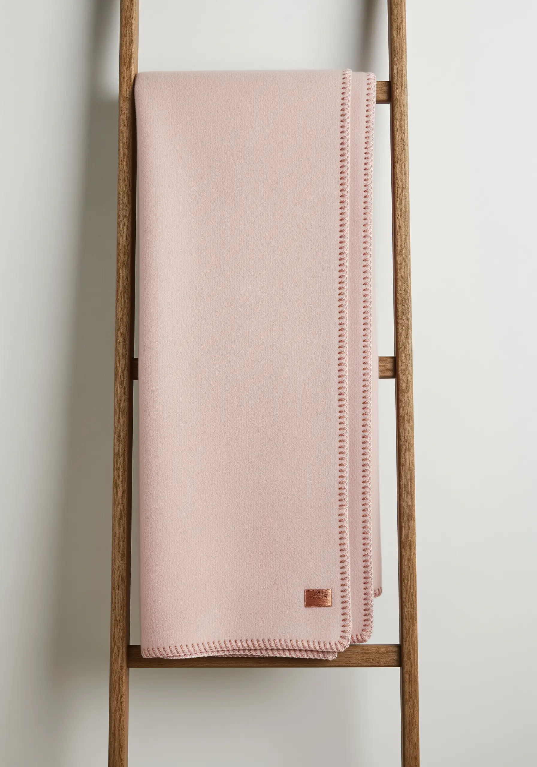 Close-up of a neat blanket stitch finishing the edge of a soft pink throw.